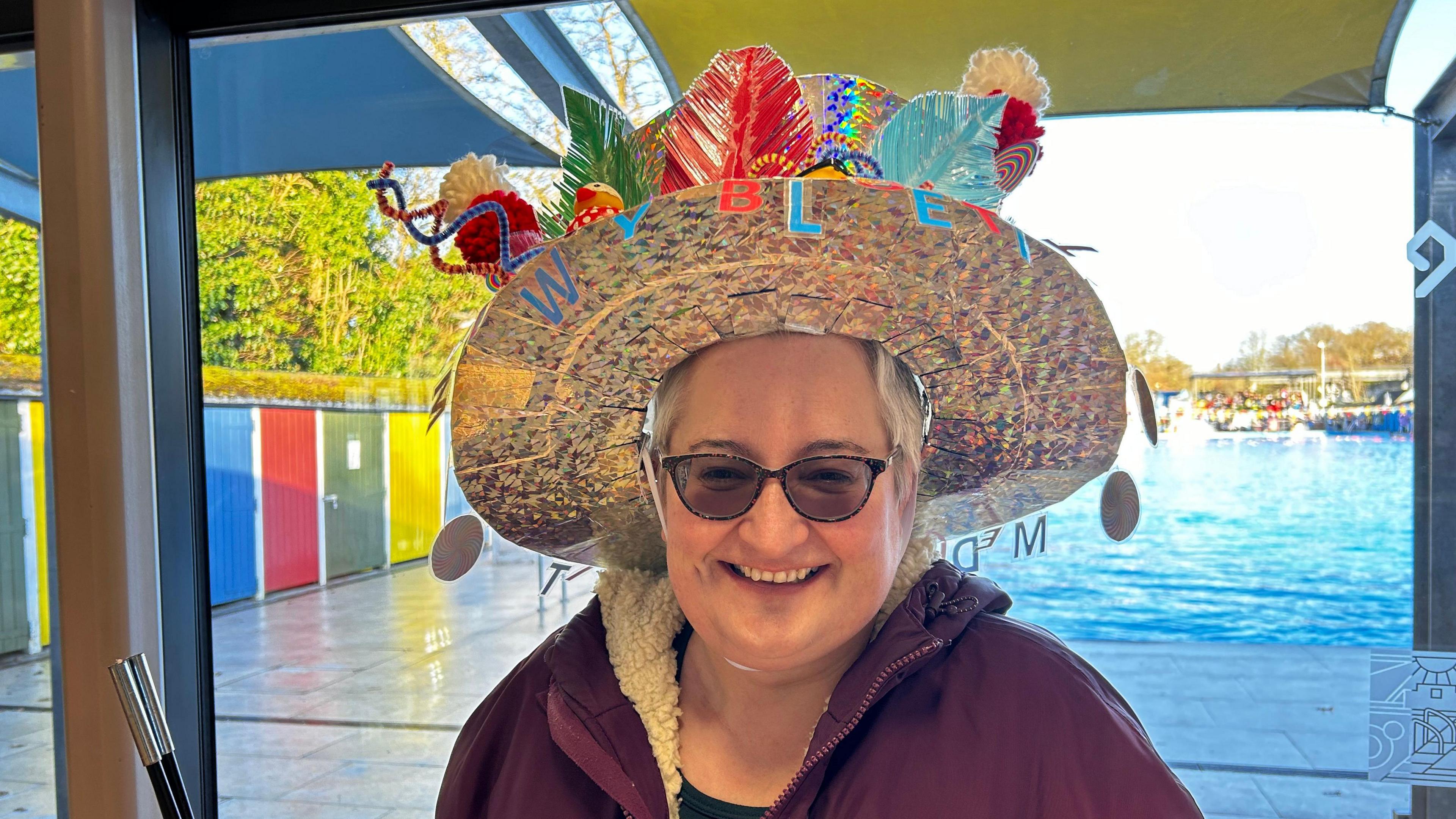 A woman wears a hat decorated in colourful leaves.