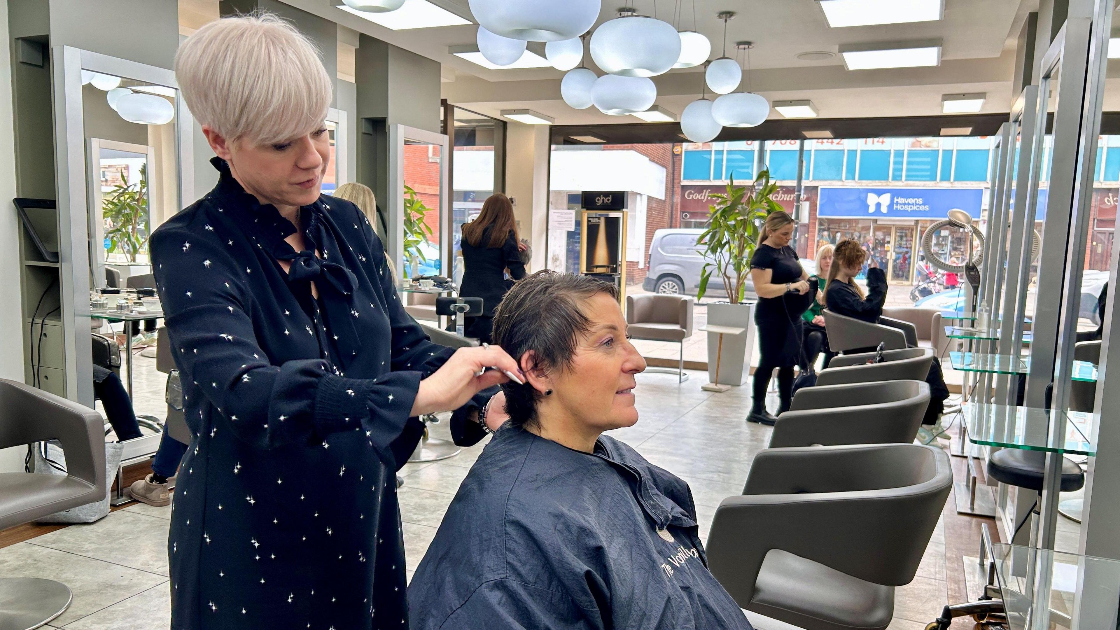 Kerry Larcher styling a client's hair in a hair salon