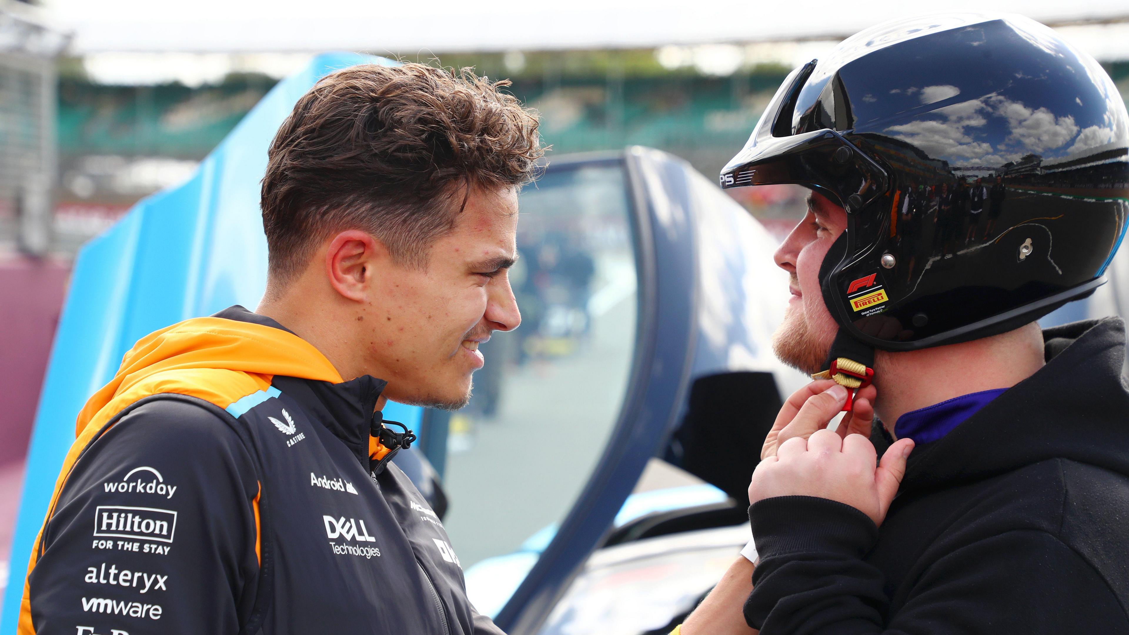 Lando Norris of McLaren talks with Luke Littler as they prepare for a Hot Lap during previews ahead of the 2024 British Grand Prix at Silverstone