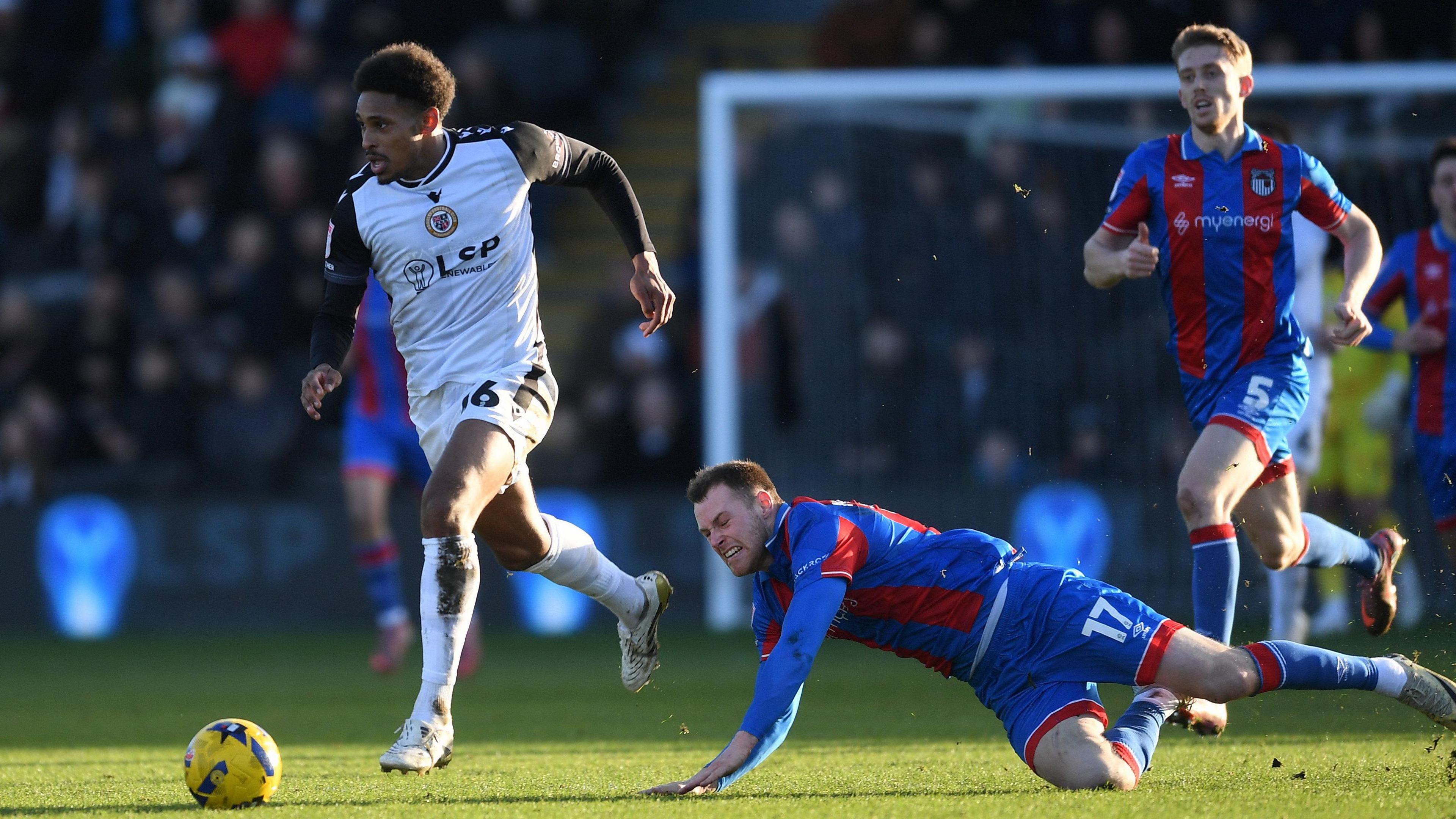 Will Hondermarck takes the ball past a Grimsby Town defender who falls to the ground