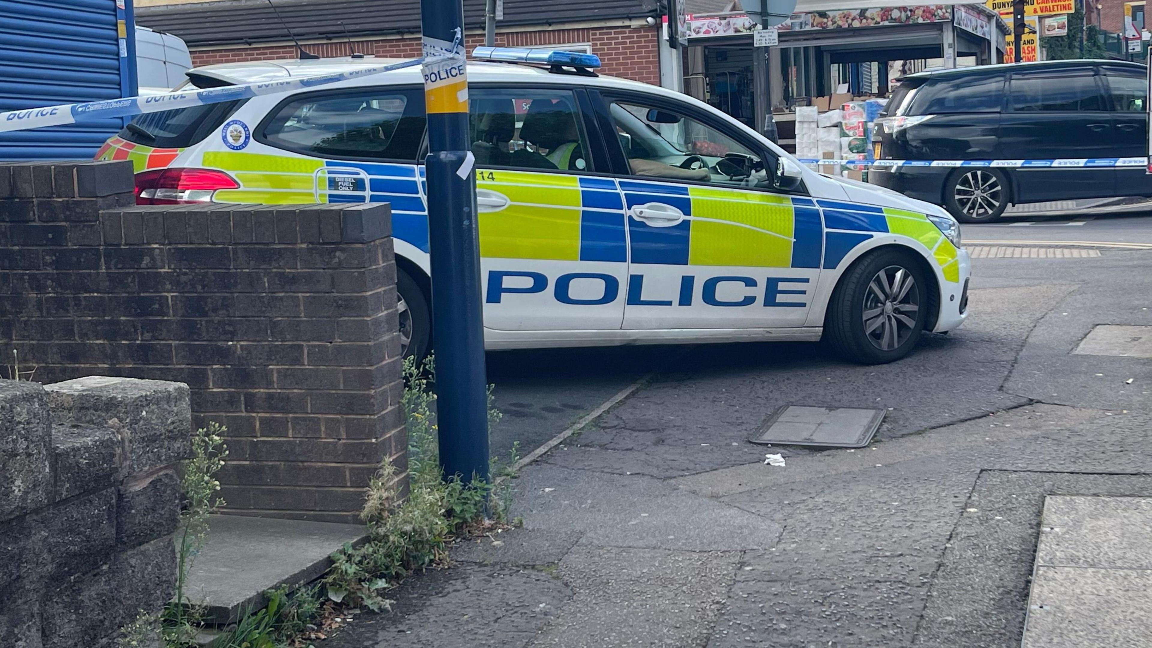 A police car parked behind the police cordon on the foothpath