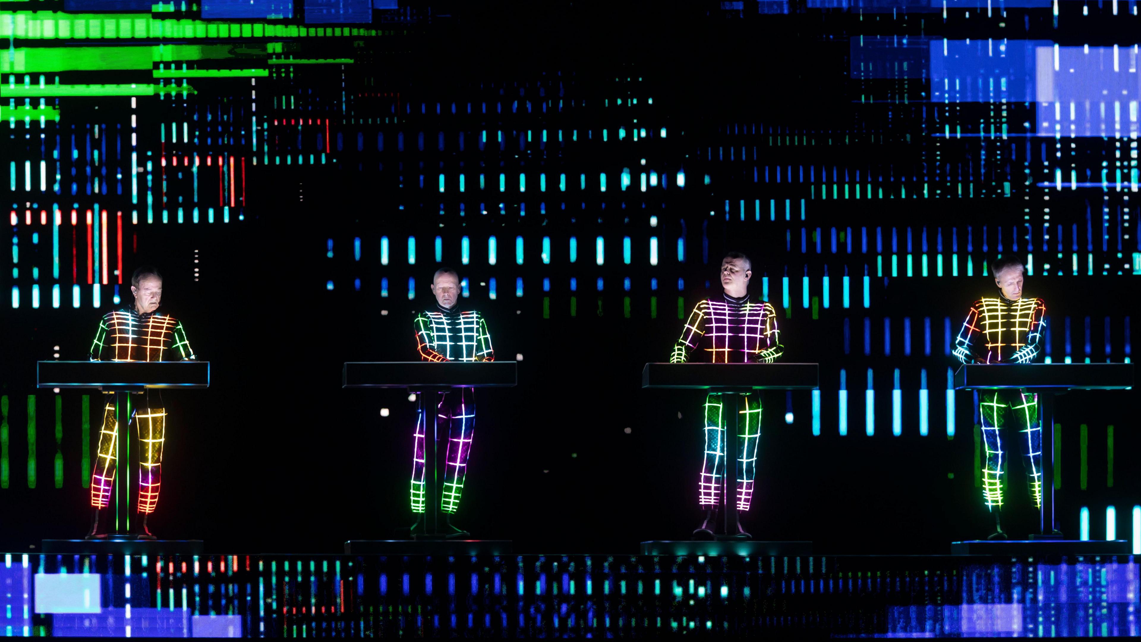 The four members of electronic band Kraftwerk performing on a stage.