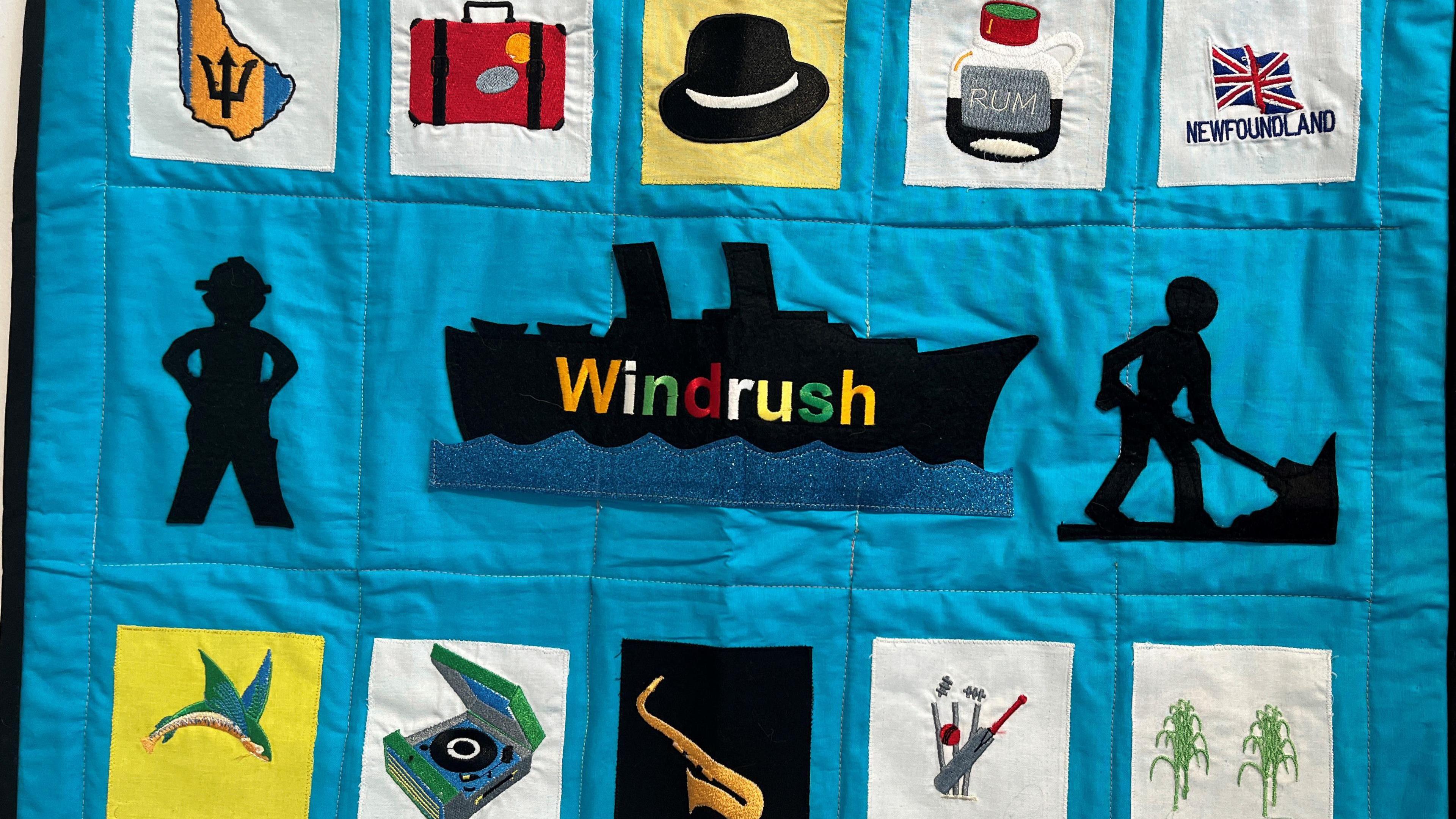 A quilt with squares around a boat silhouette, the squares have images of a record player, cricket stumps and a bottle of rum 