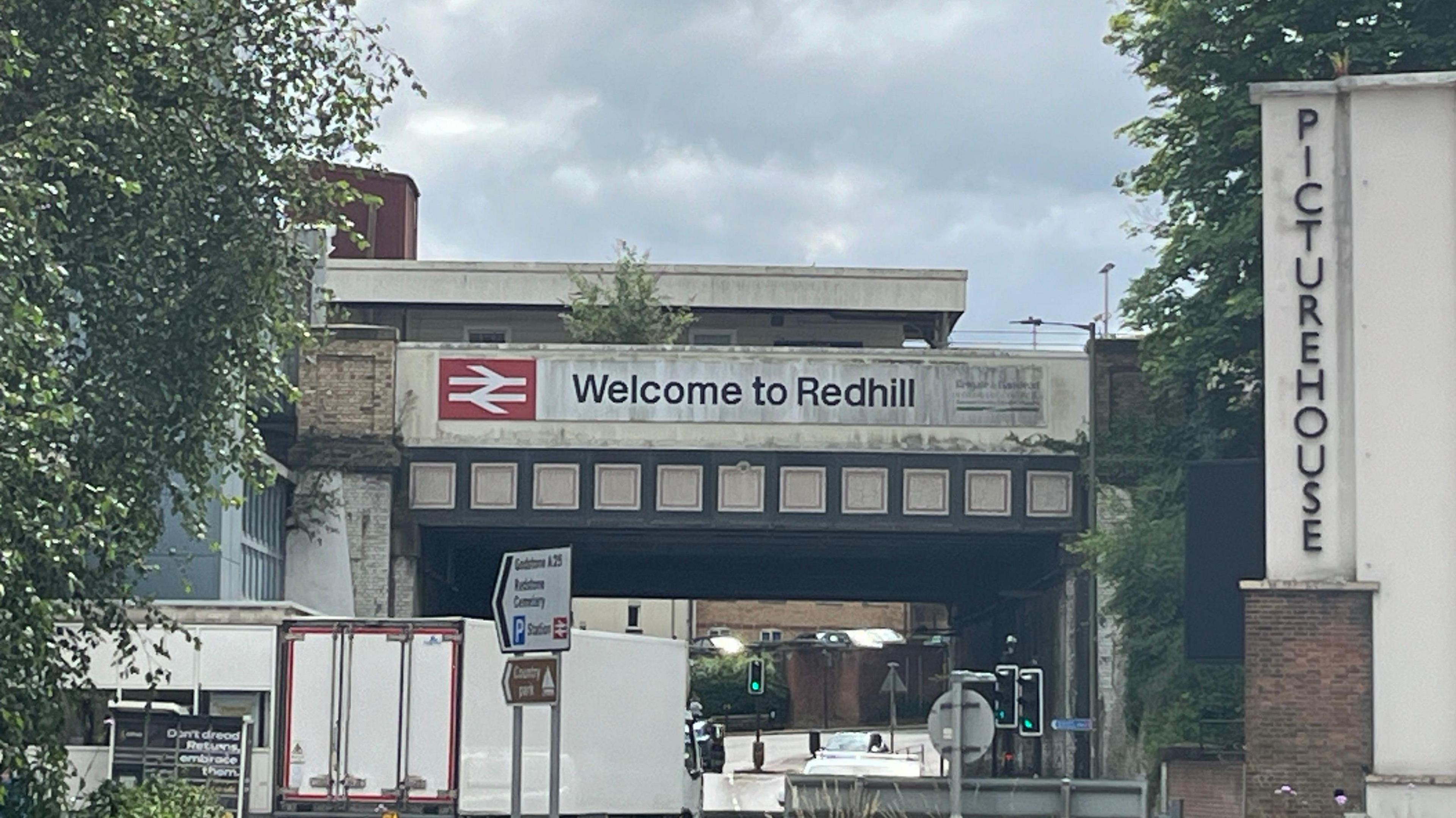 A welcome to Redhill sign on a bridge 