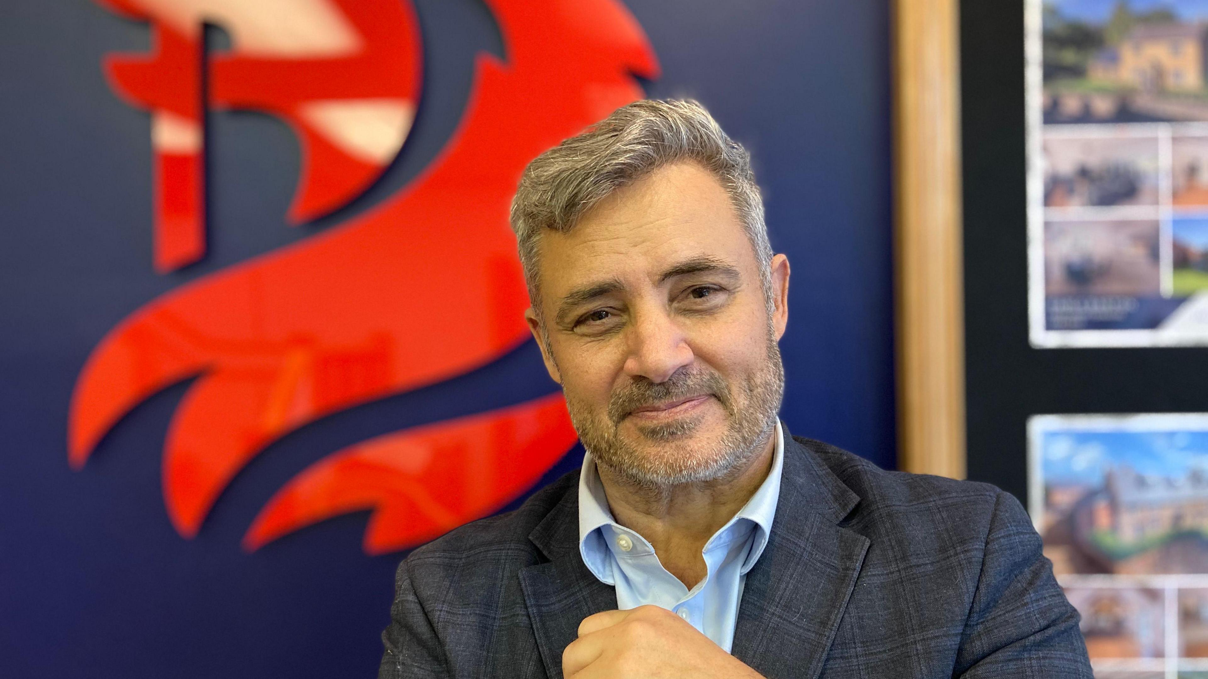 Nick Paterson smiles directly at the camera wearing a blue suit jacket and blue shirt.