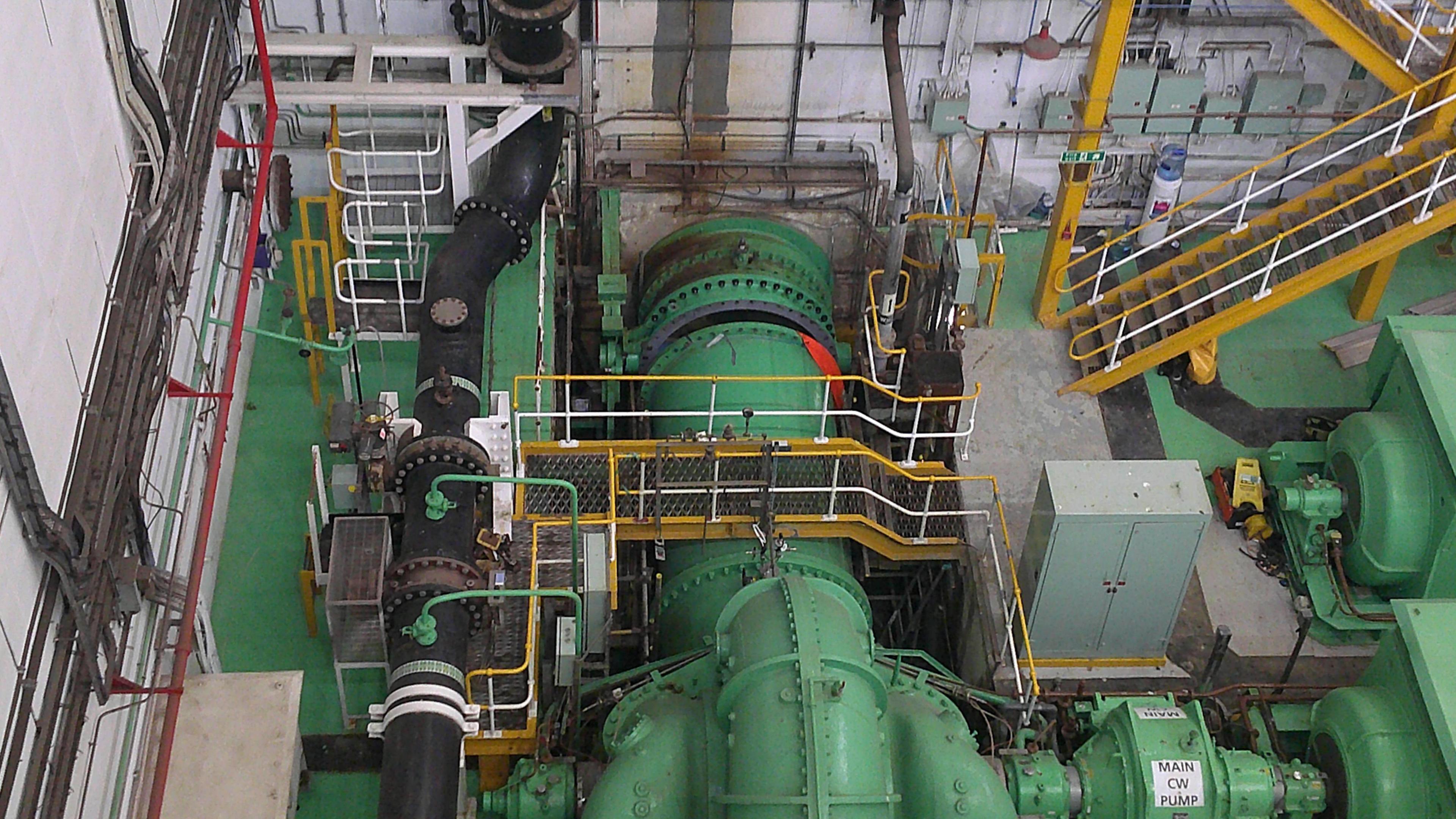 Machinery inside Dungeness B, with pipes painted green and walkways and ladders painted grey.