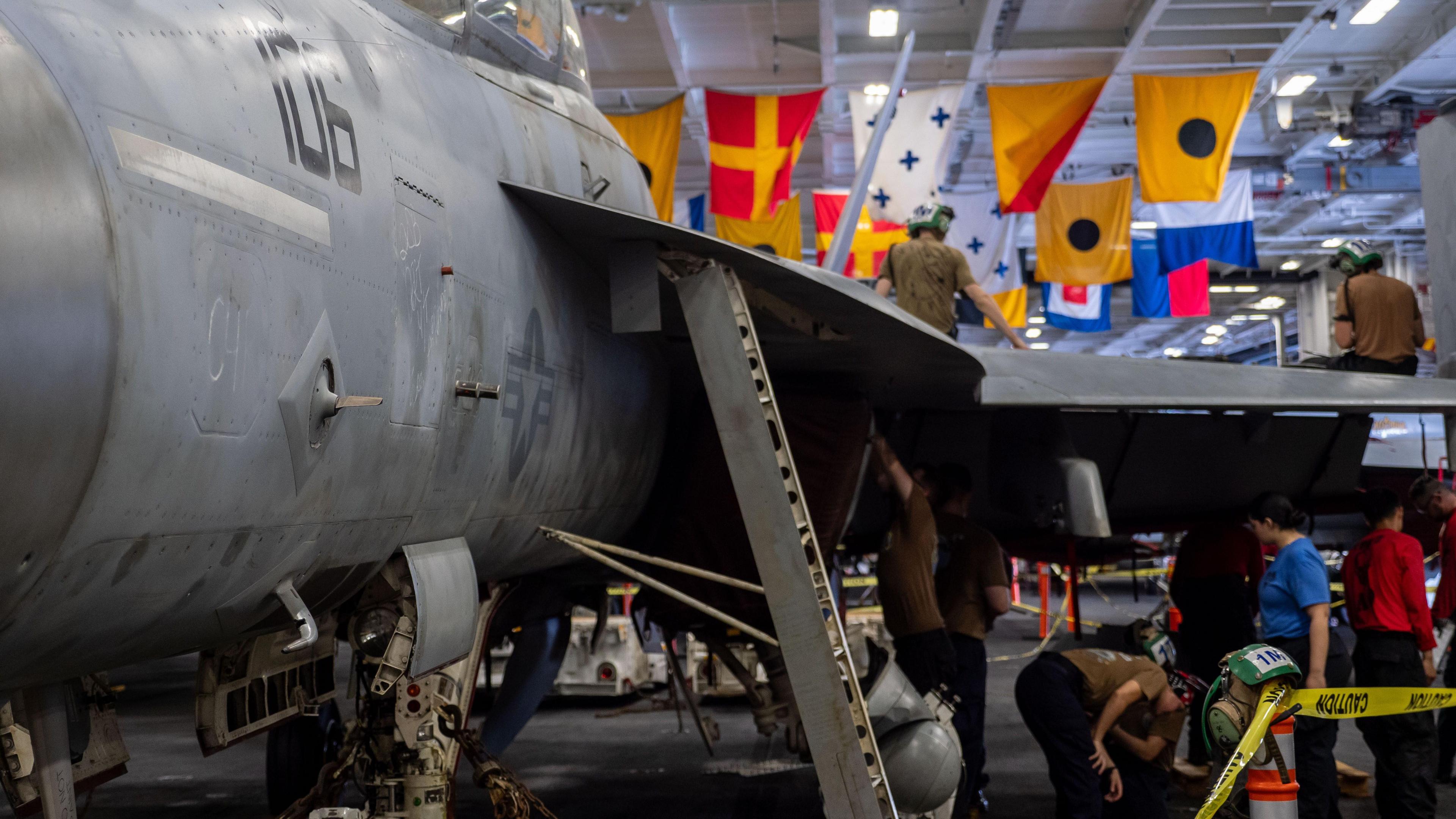 Crews maintaining an F/A18 in the Carl Vinson’s hangar