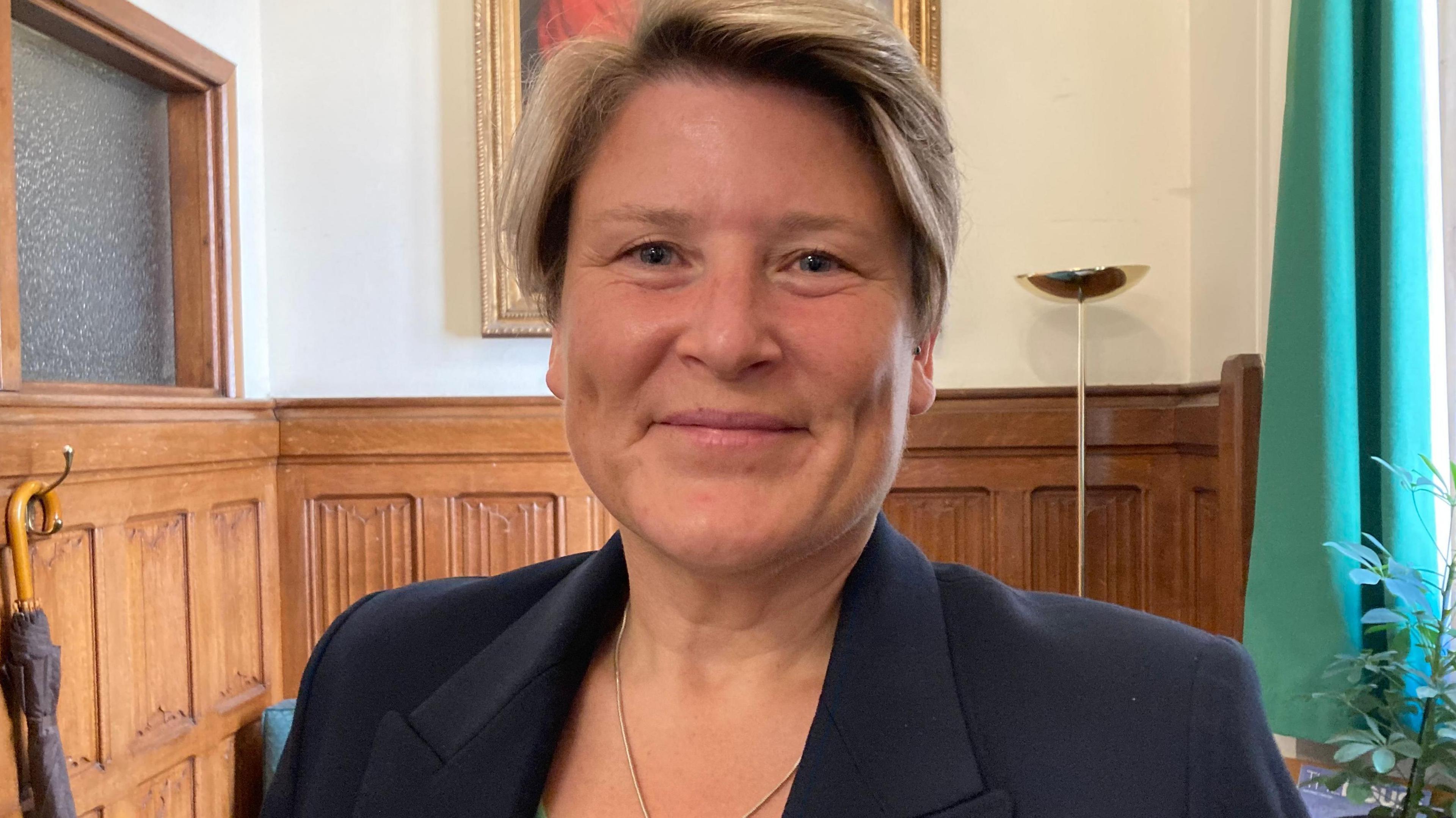 Sarah Dyke smiling at the camera in a Parliamentary room