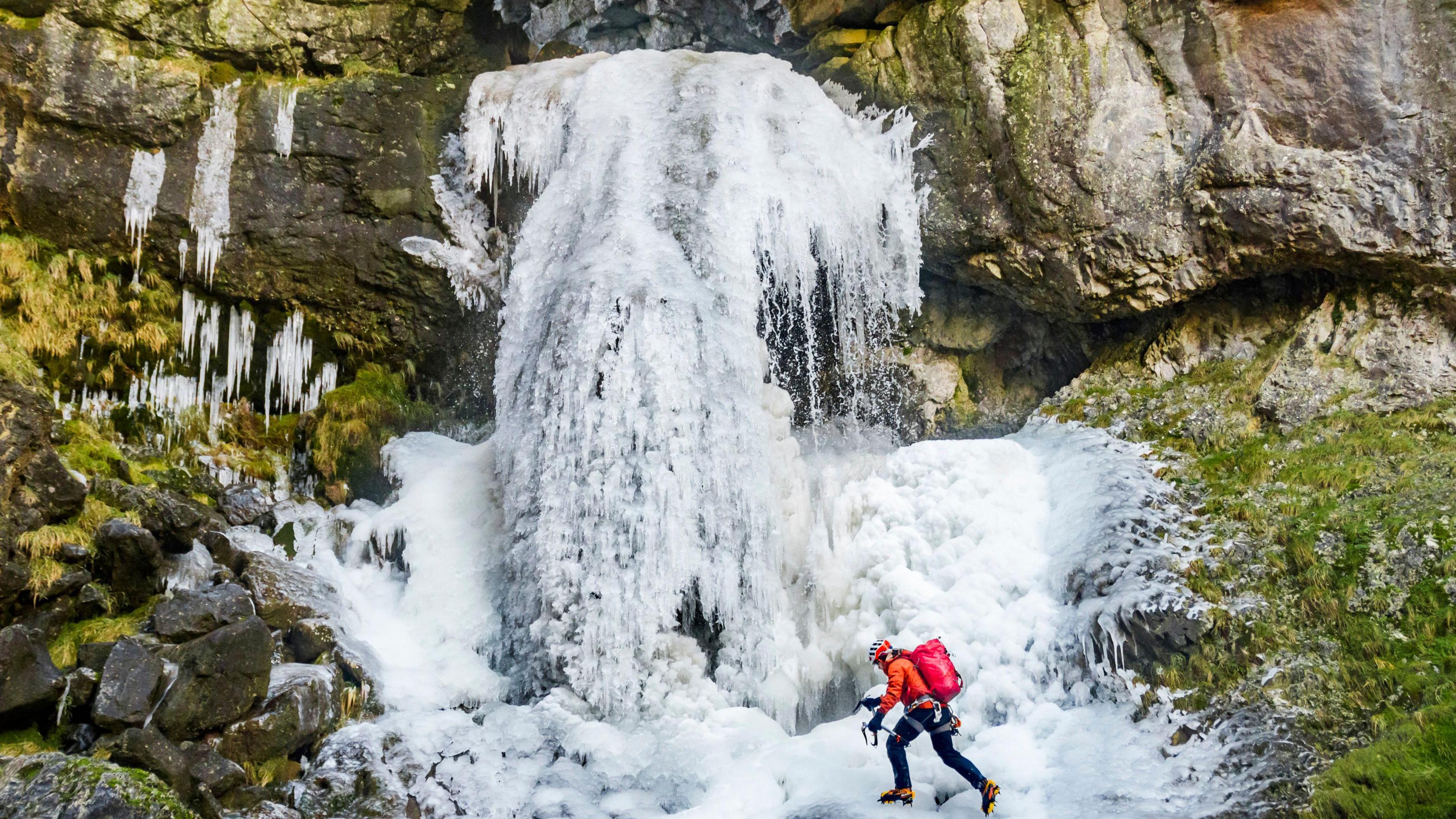 A man climbing a frozen waterfall in the Yorkshire Dales National Park.
