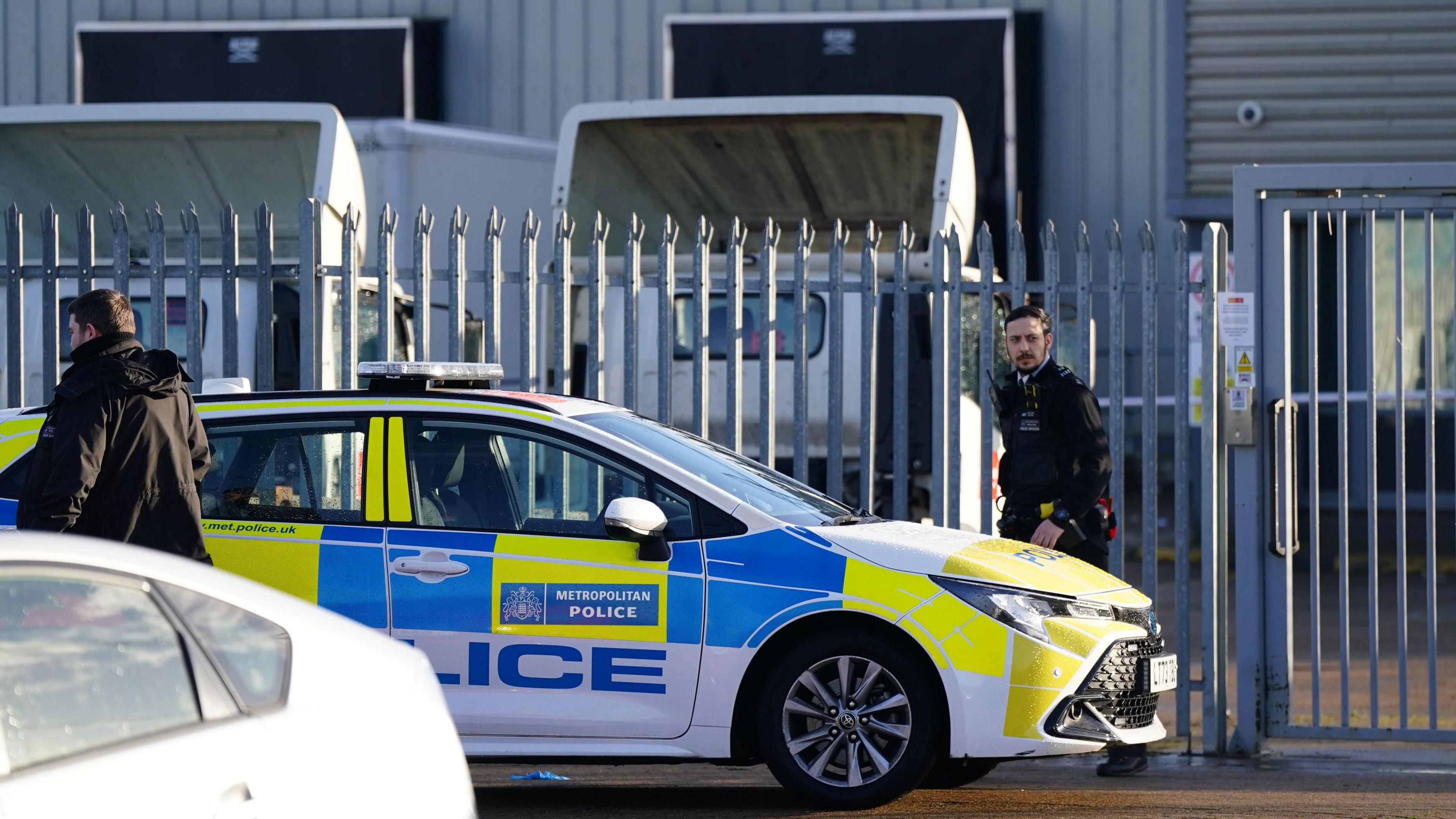 Police stand near police car in industrial area 