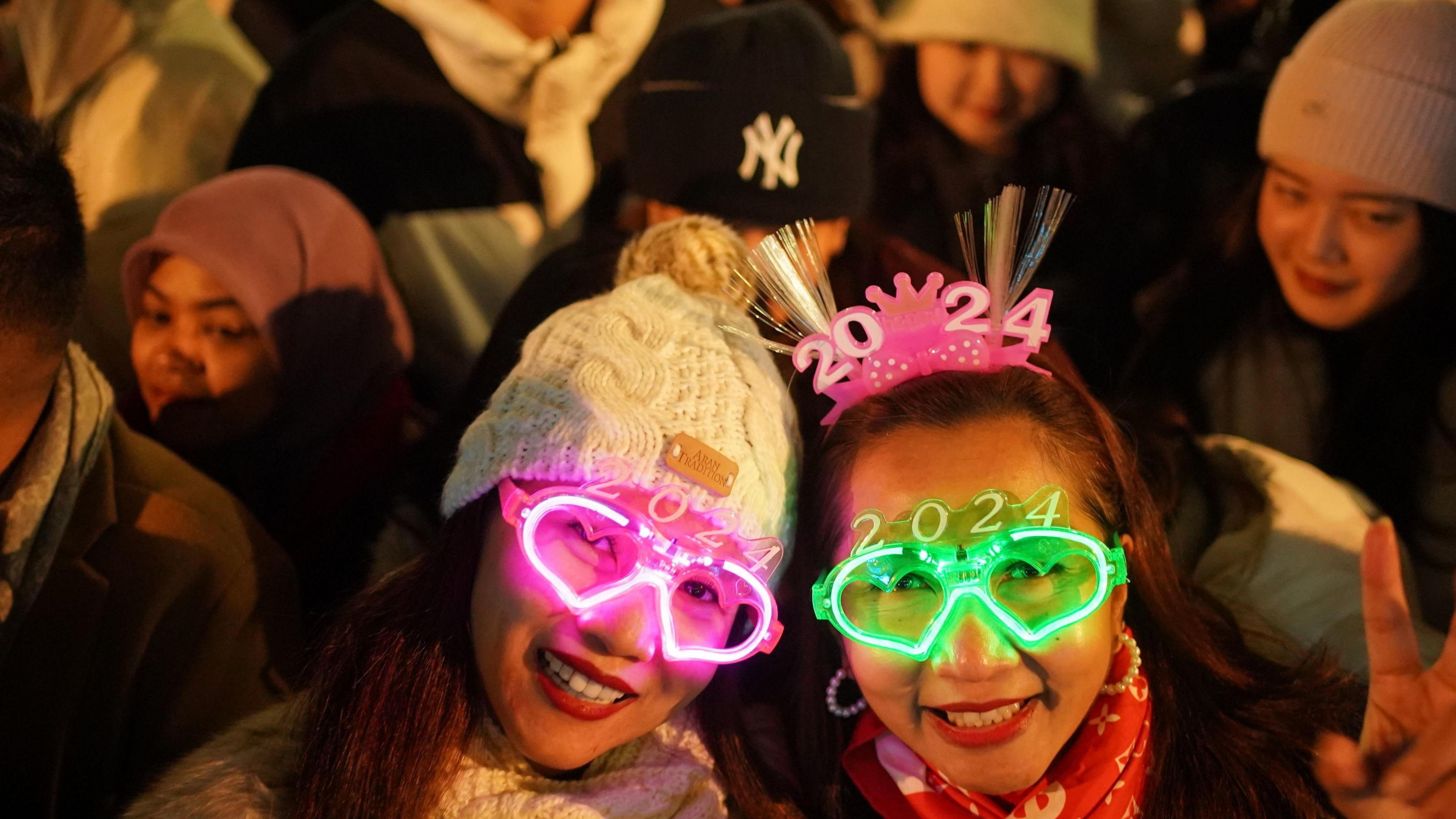 Two women stand in a crowd wearing 2024 glasses