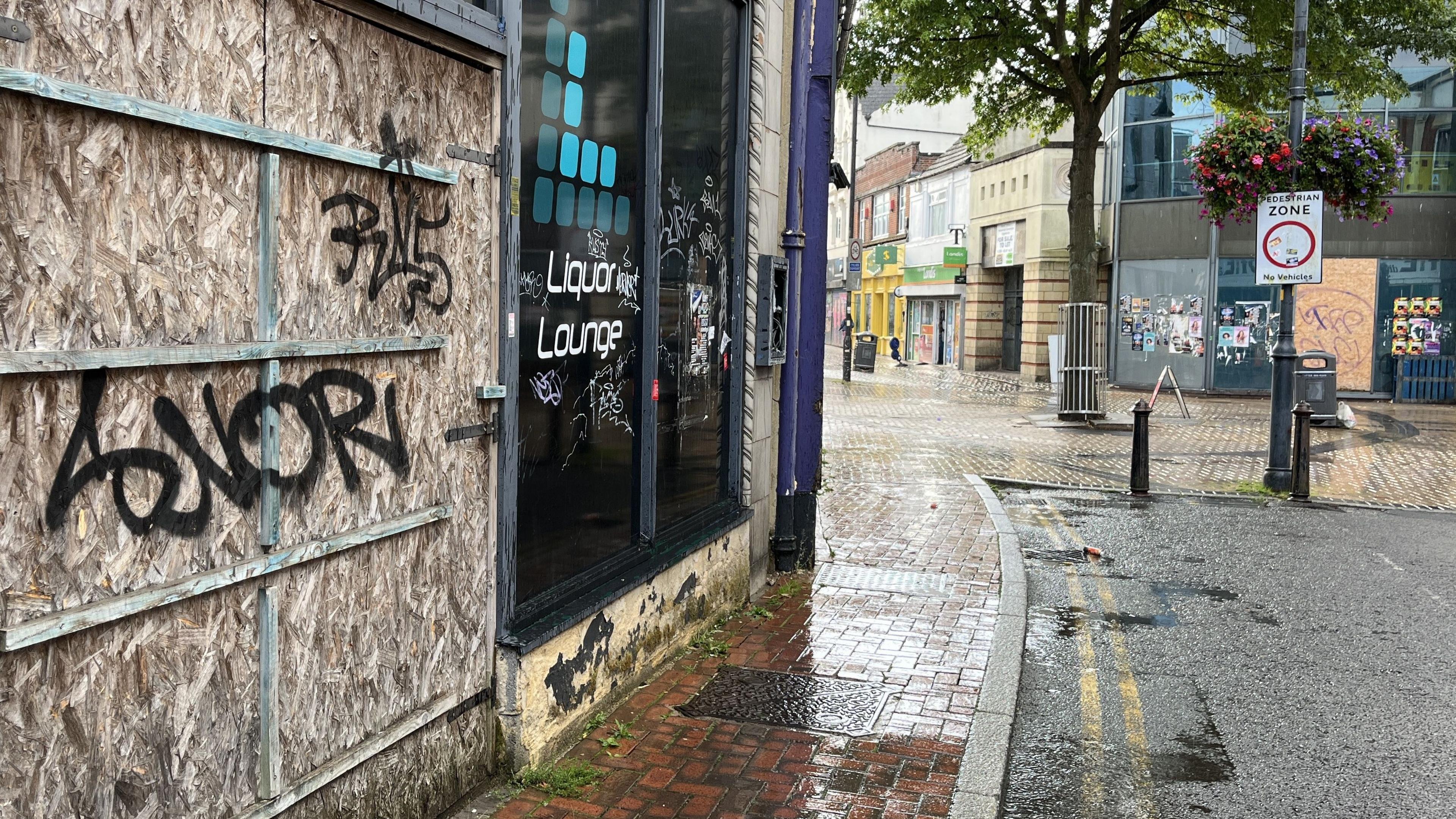 A boarded up businesses covered with graffiti tags
