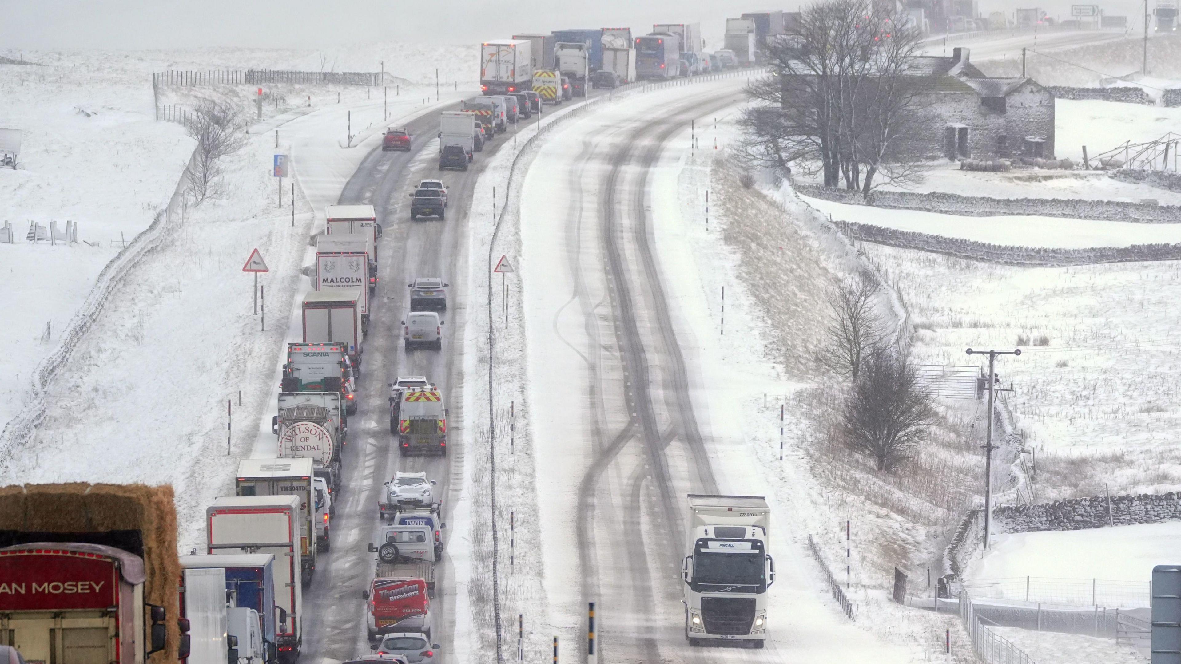 Cars queuing on an uphill road covered in snow