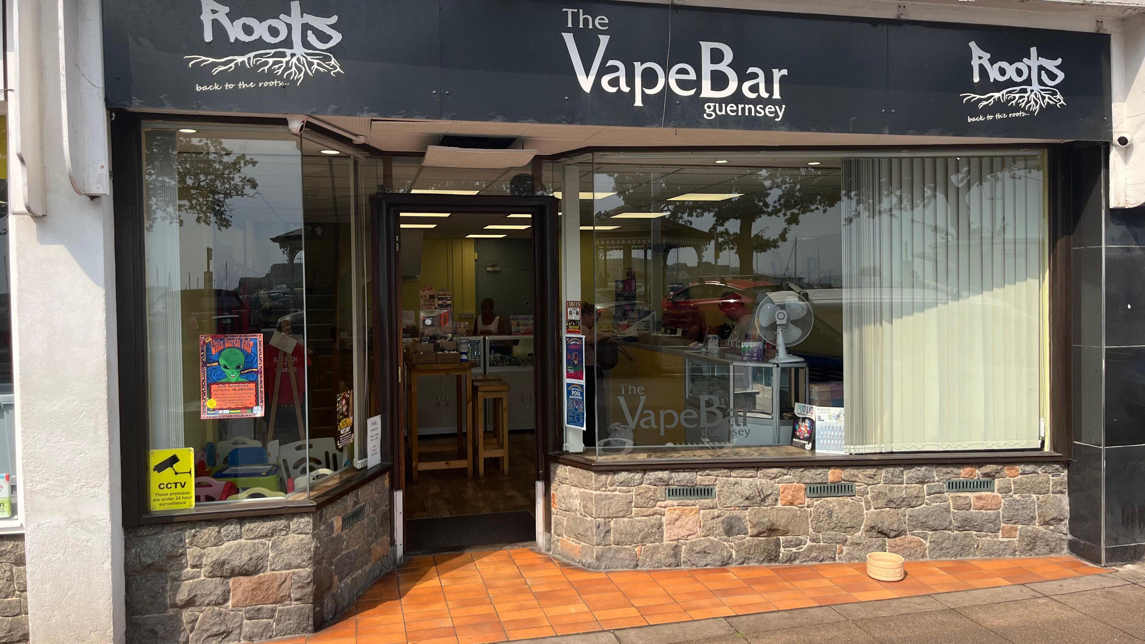 The Vape Bar in St Peter Port. It is a shop with large glass windows and yellow blinds.