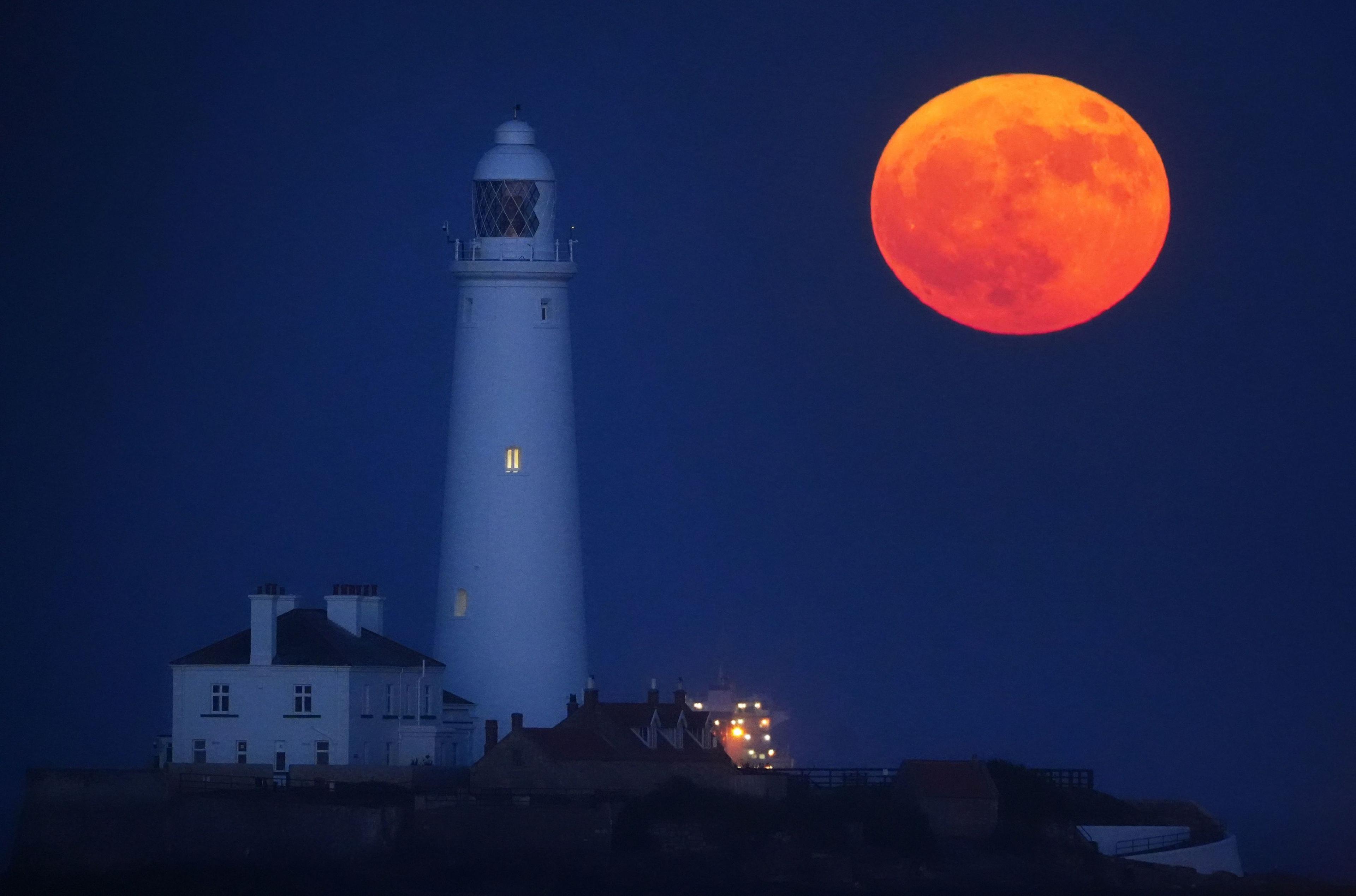 The full moon, also known as the Flower Moon, rises through the sea mist at St Mary's Lighthouse in Whitley Bay. on the North East coast of England.