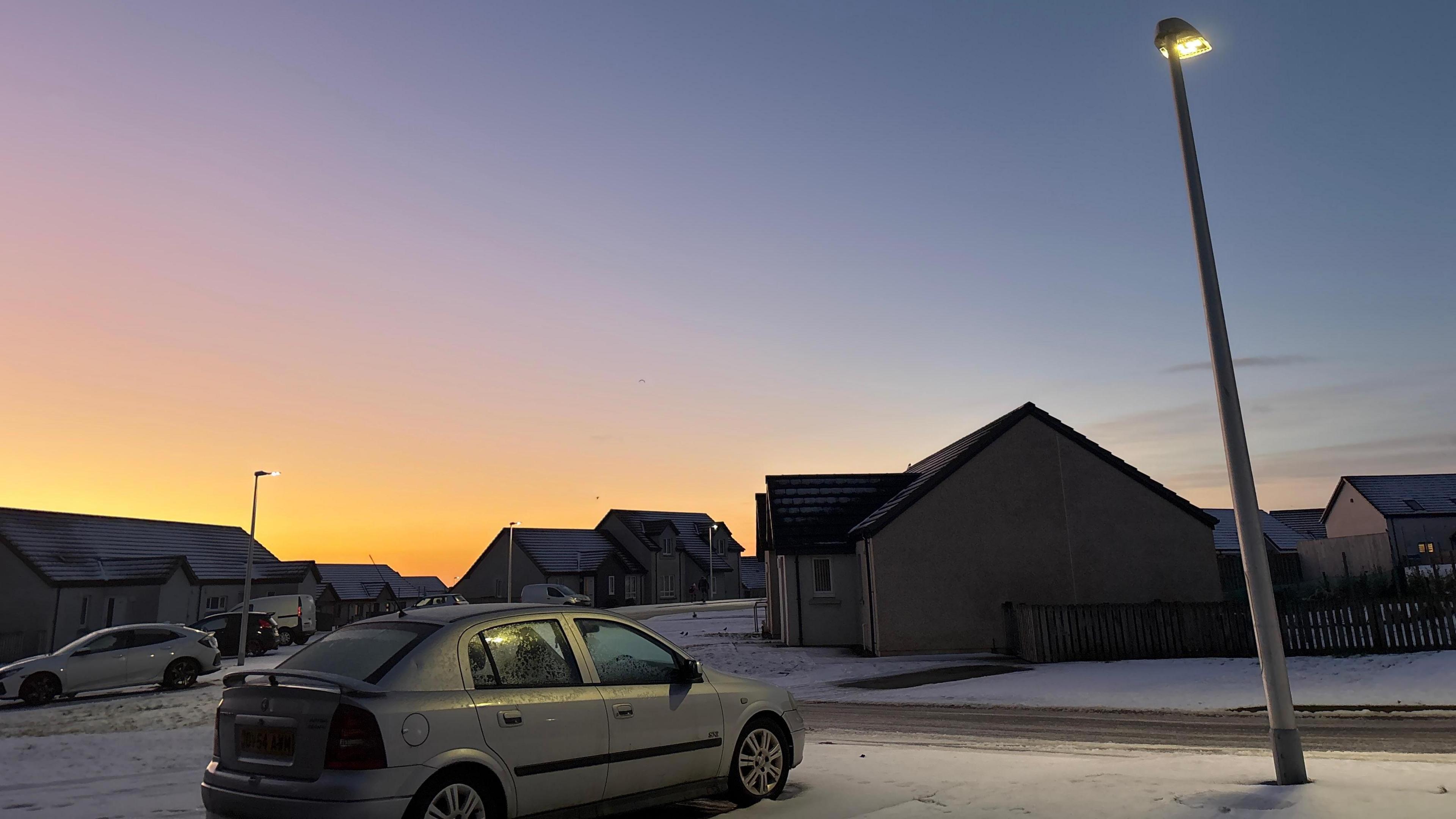 Car parked on snow beside a lamp post