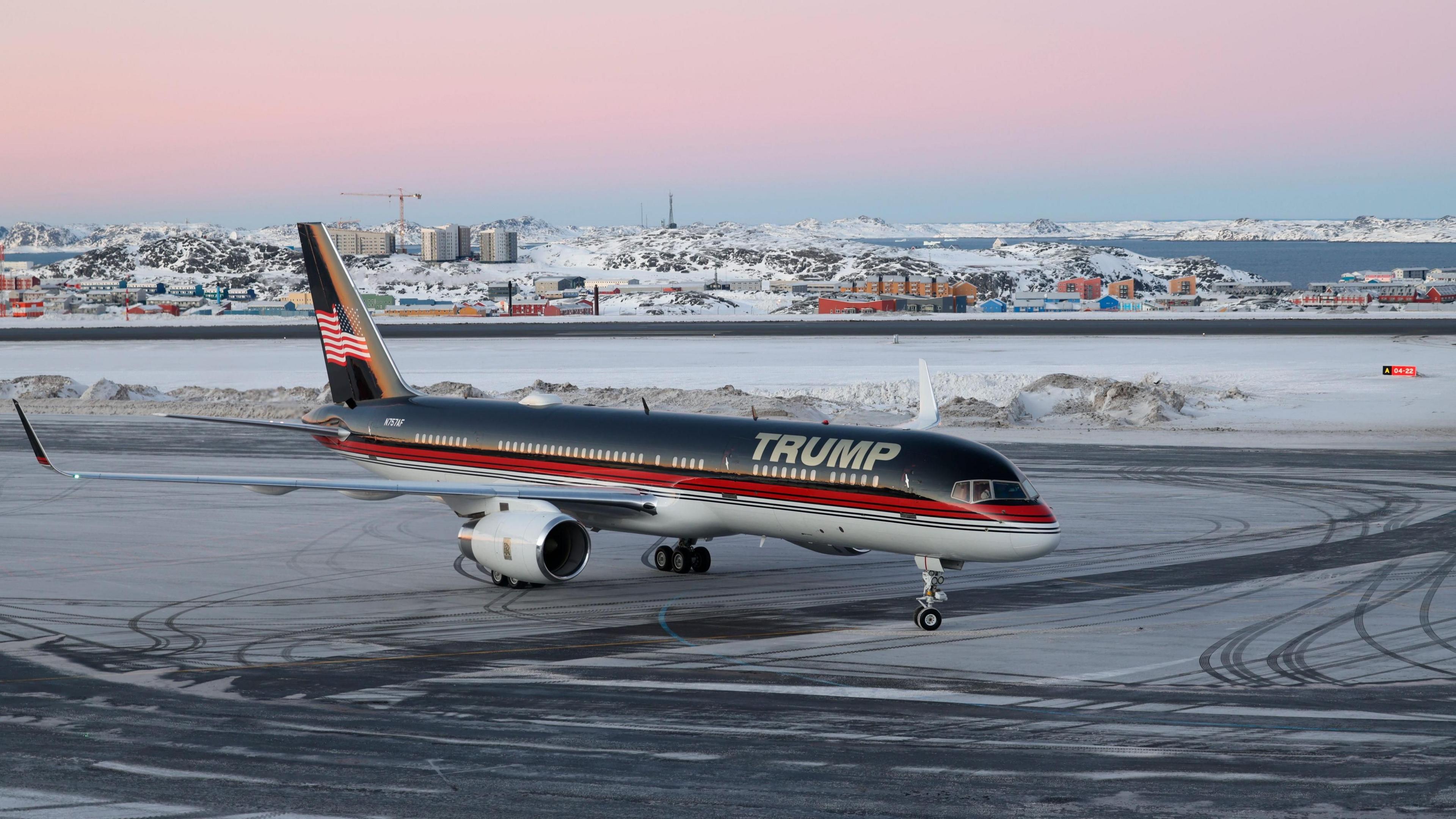 A blue, red and white jet with Trump written on the side standing on an icy runway in Greenland