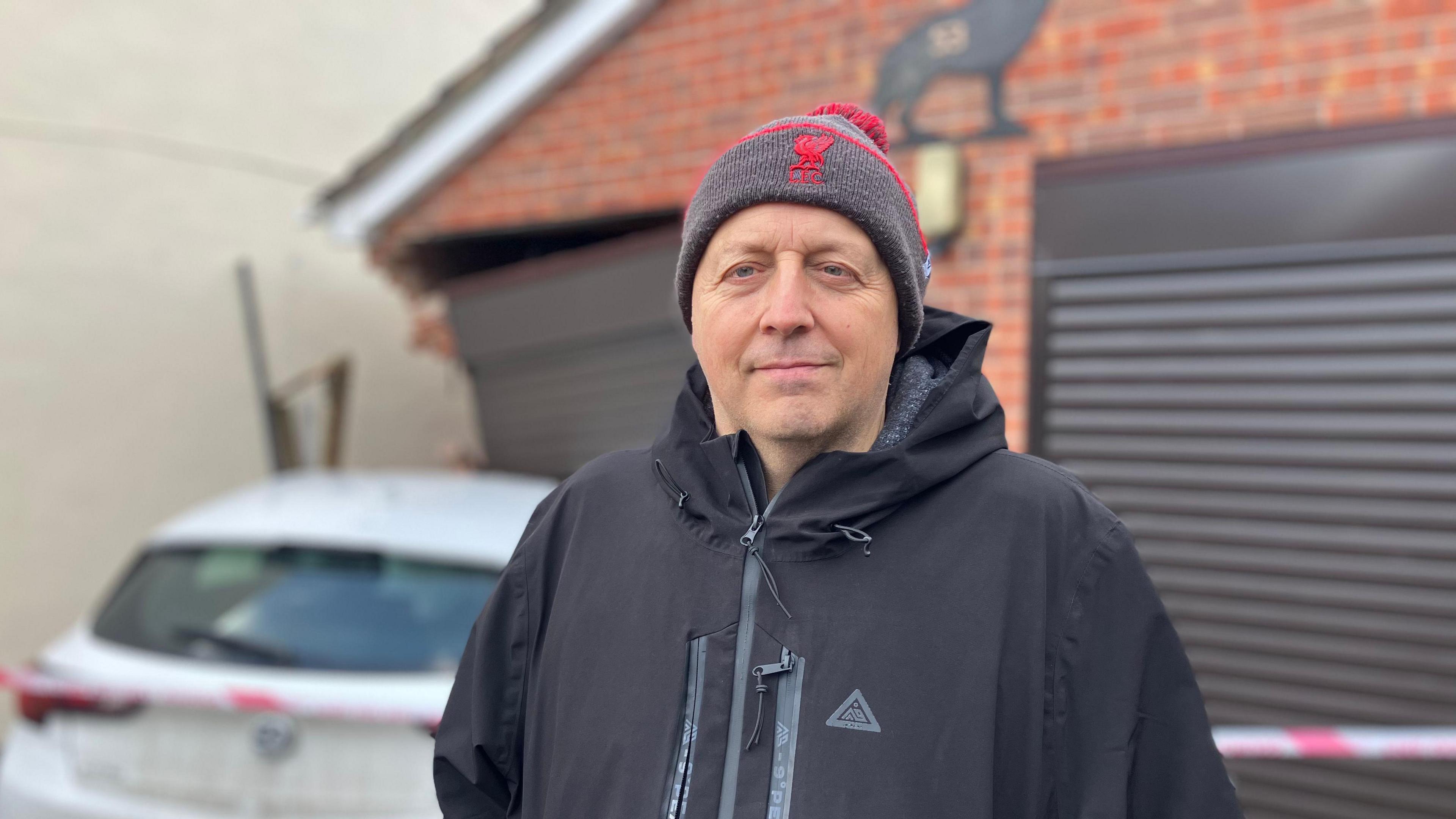 An image of Andrew Brown wearing a Liverpool FC bobble hat and black coat