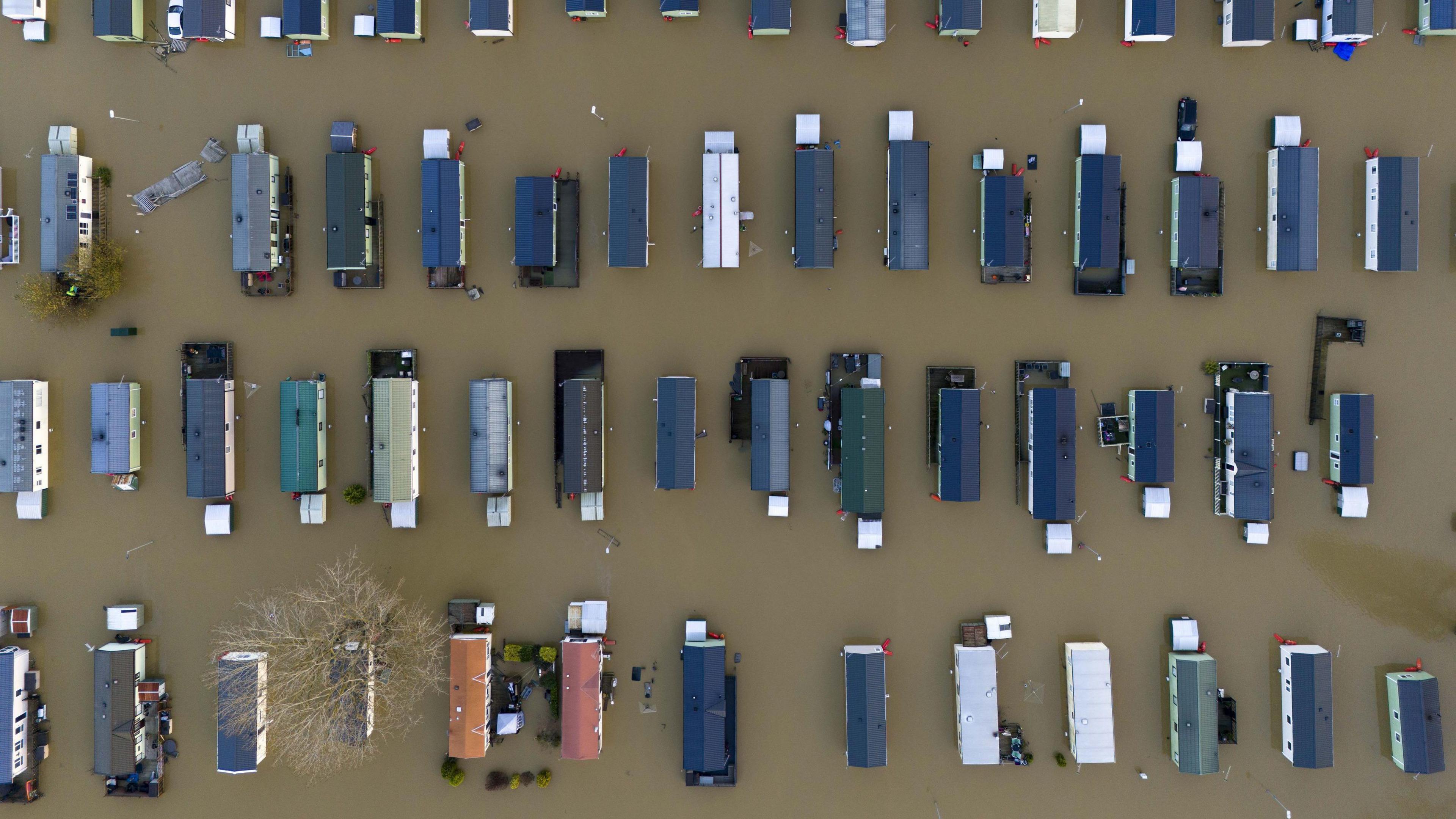 A drone image taken at Billing Aquadrome, looking directly down from height on about 60 caravans - all of which are surrounded by the same brown floodwater.