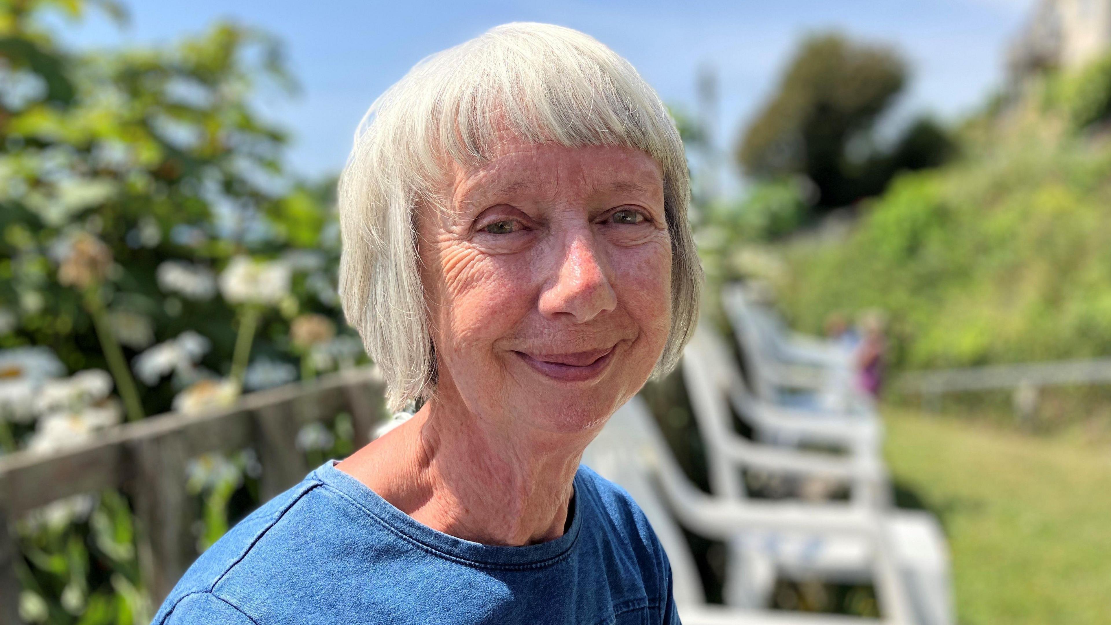 Woman with short white hair smiling at the camera