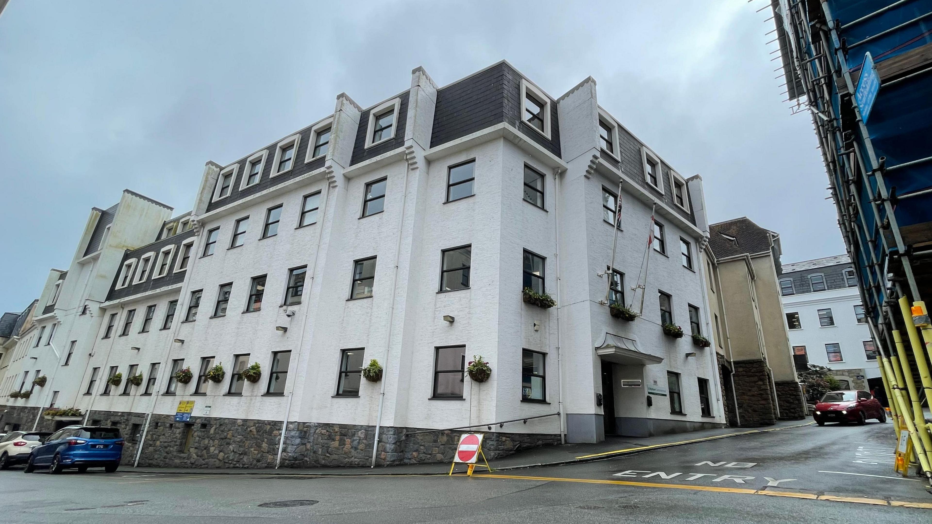 Edward T Wheadon House - A large grey and faded white building with lots of windows. In front of a road, with a road closed sign in it.