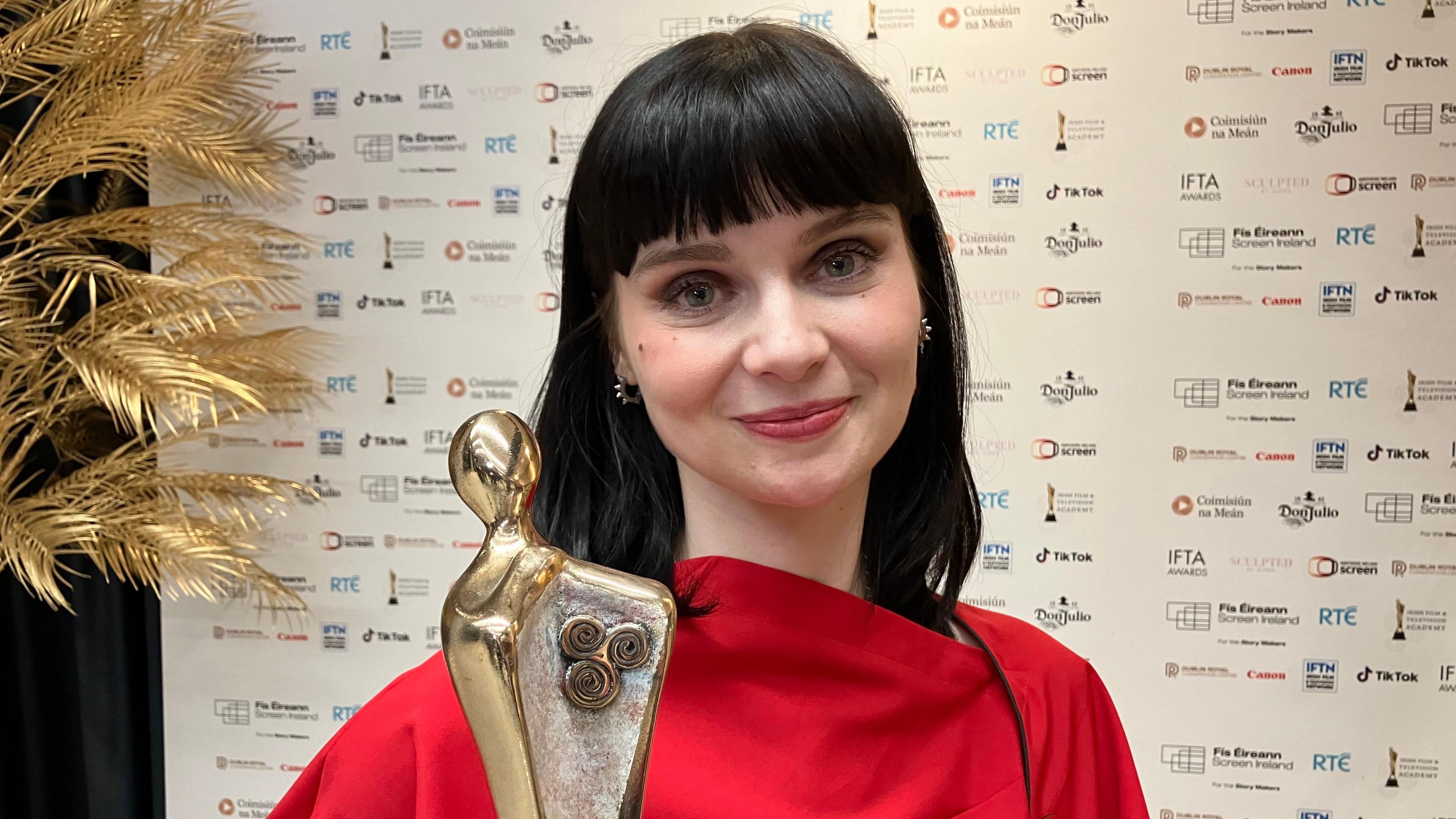 Lola Petticrew in a red dress holding the award