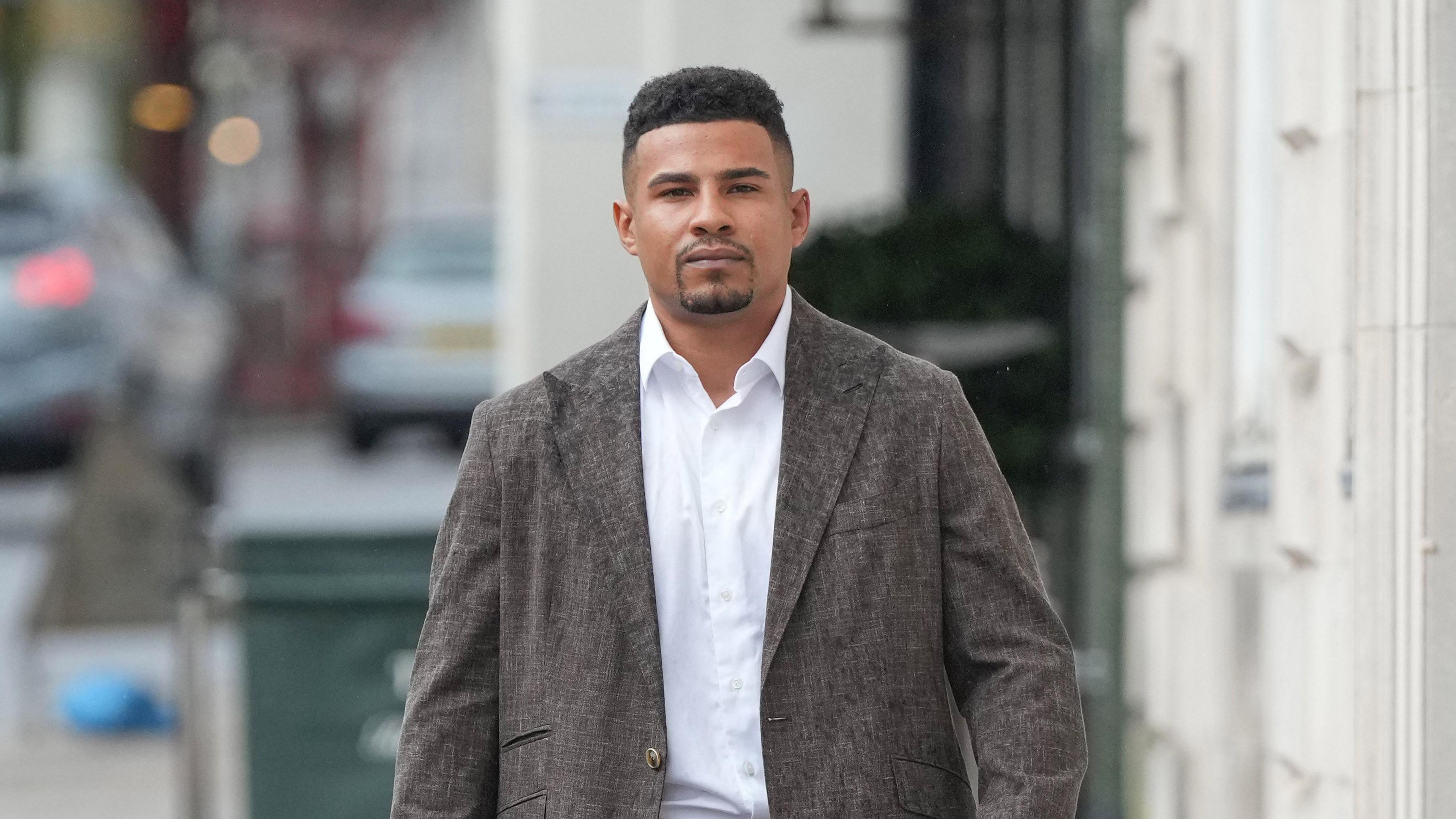 Joseph Eubank, young man in brown suit with white shirt, walks down a street