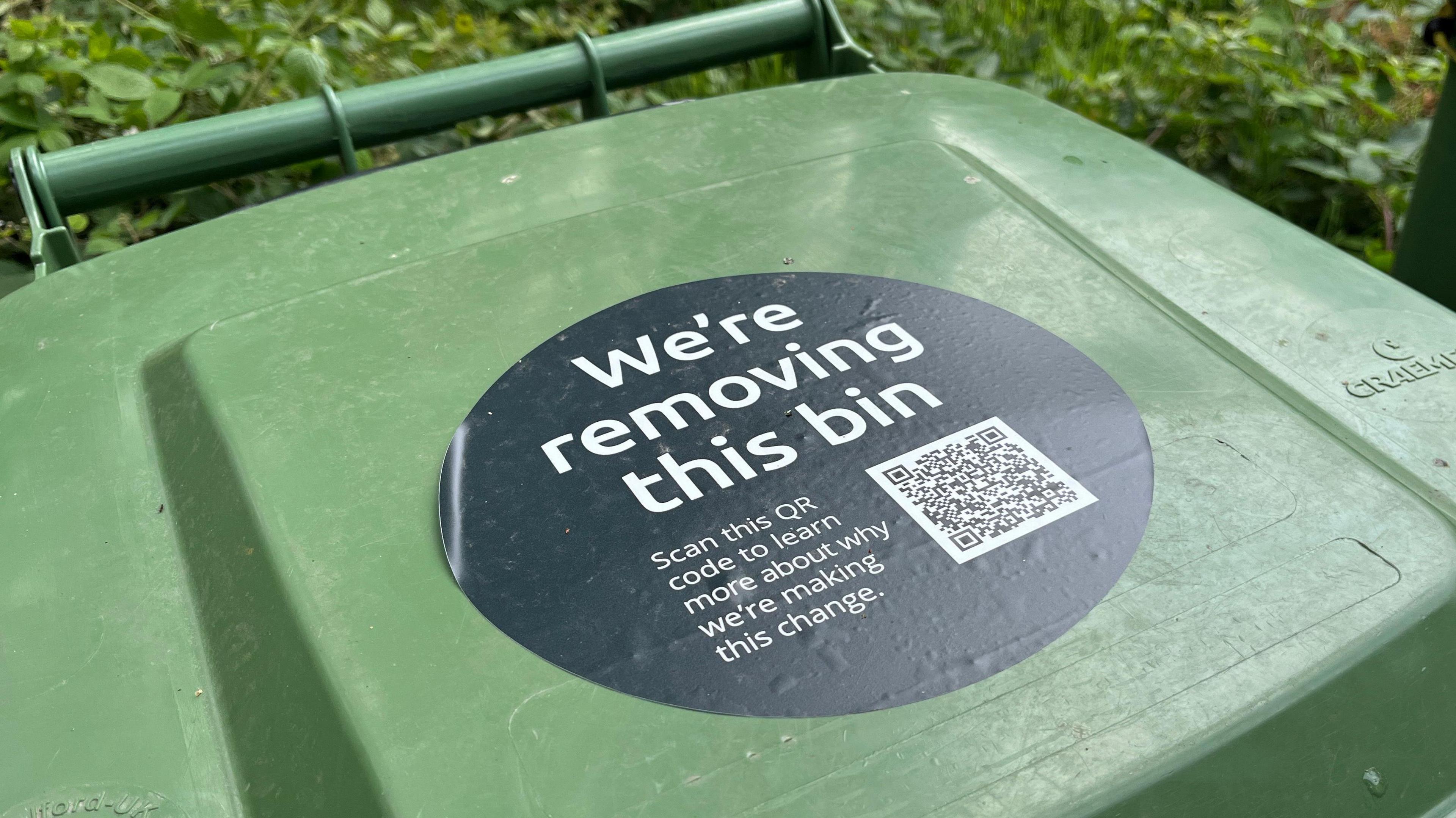 Green bin with a sign warning the bin is going to be removed
