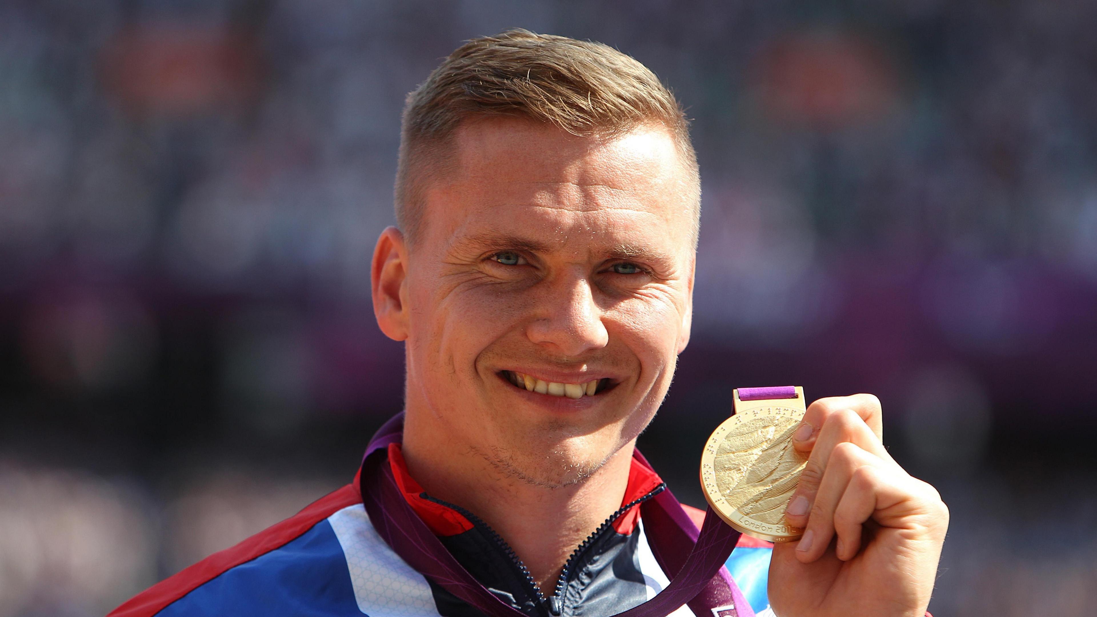 Paralympic gold medallist David Weir smiling and holding one of his medals.