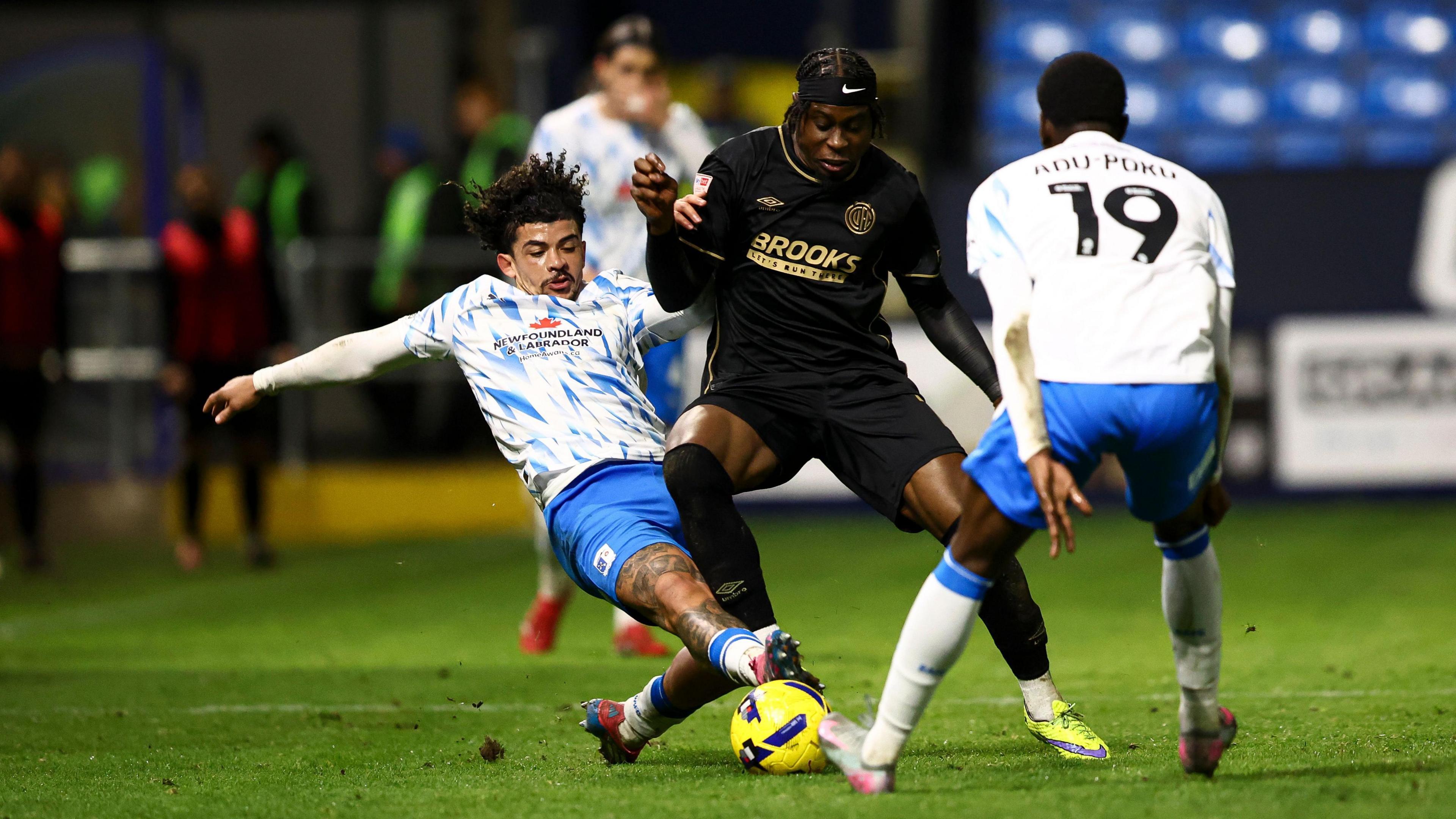 Pelly Ruddock Mpanzu of Cambridge United is tackled by Josh Gordon of Barrow AFC