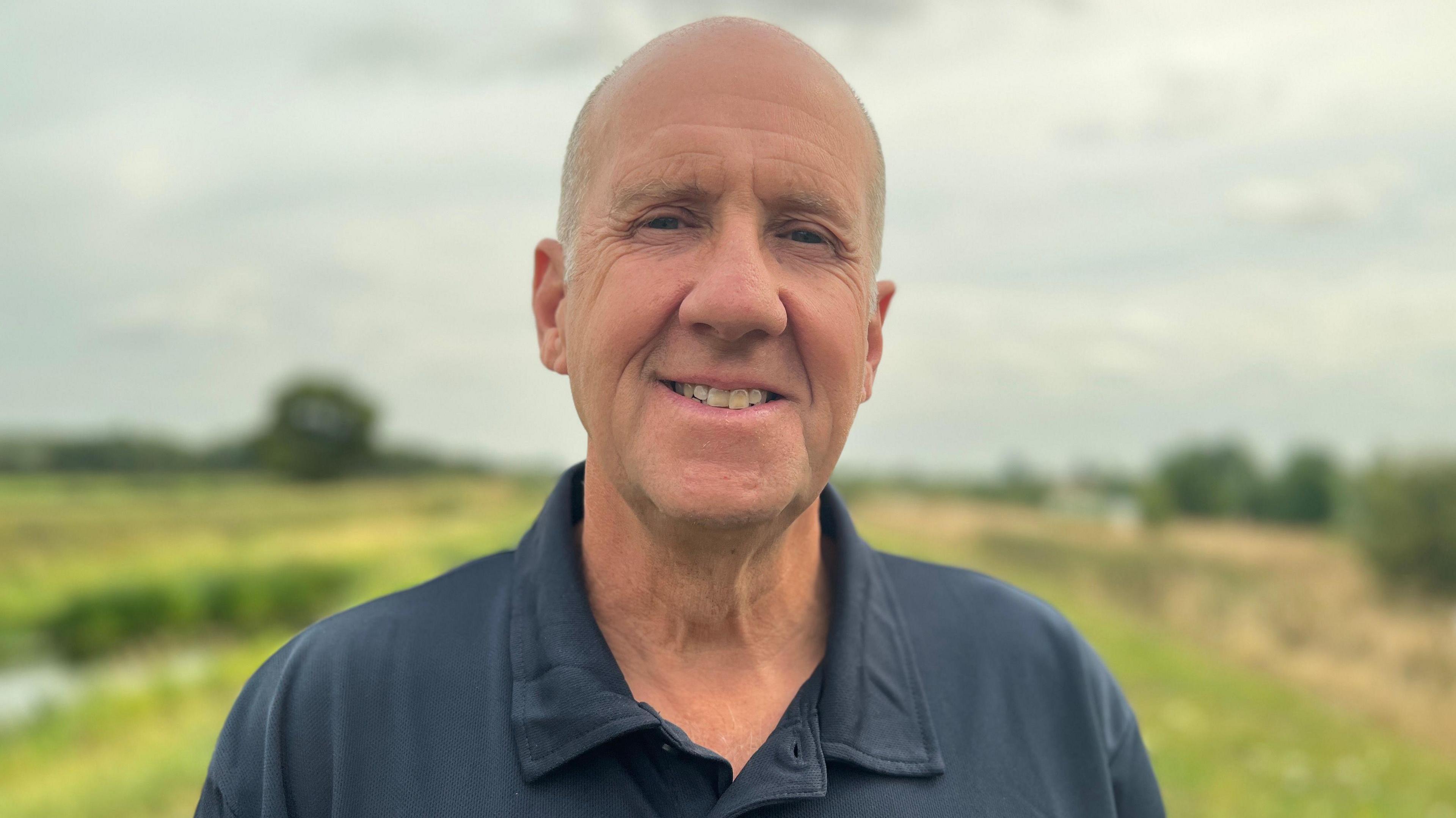 Richard Astle stood in a field wearing a navy polo shirt