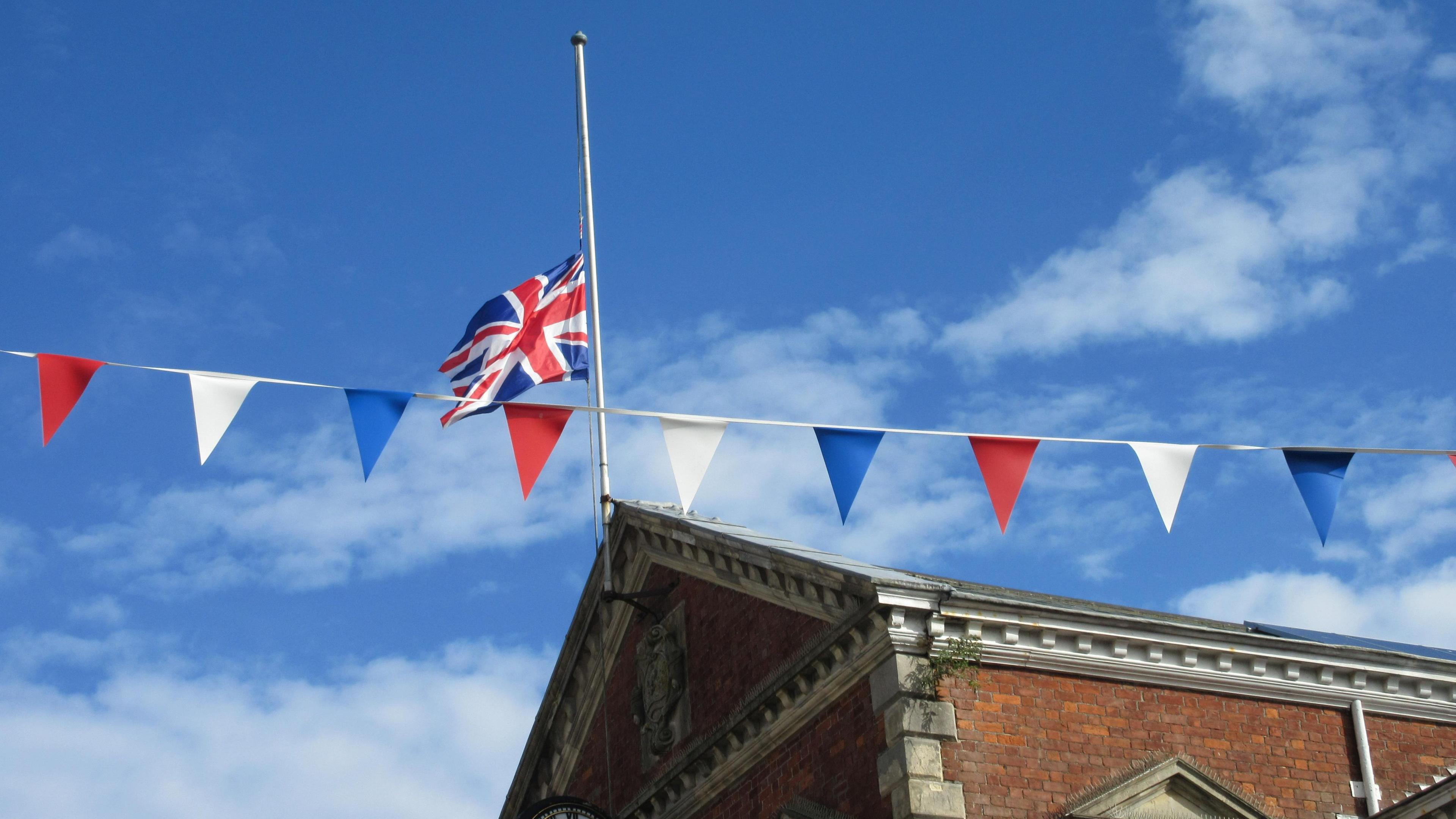 The union jack flies at half mast to mark Queen Elizabeth II's death. The flag is on top of a building in Great Torrington. Red, white and blue bunting has also been hung up