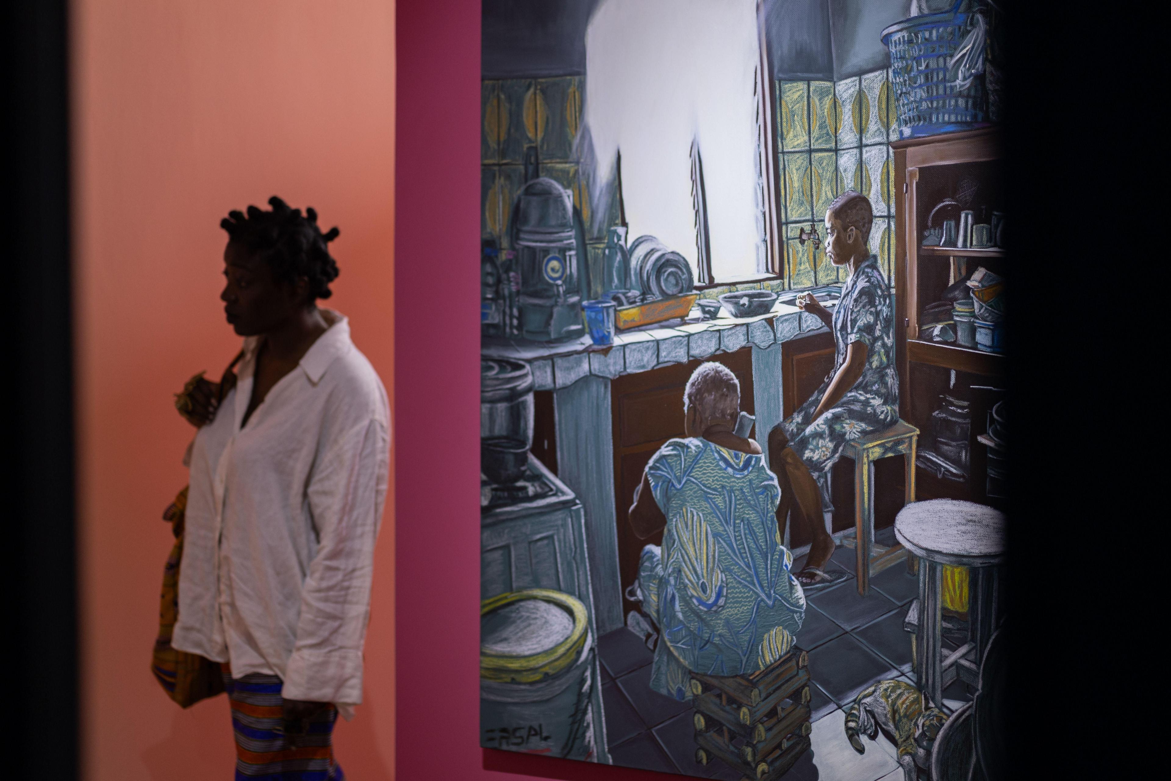 A woman walks past an intricate painting showing two figures in a kitchen.