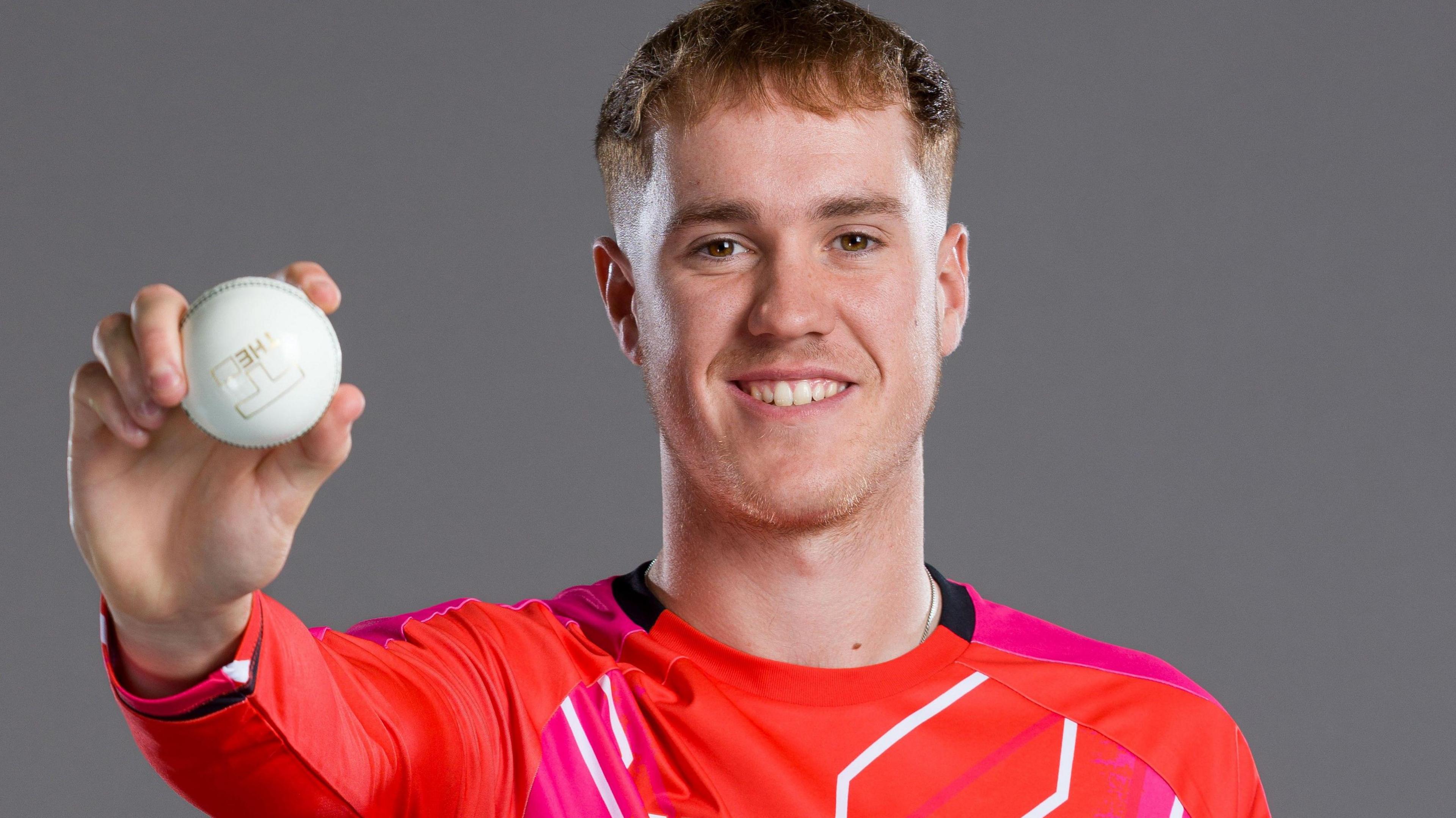 Ben Kellaway holding a cricket ball in a Welsh Fire shirt