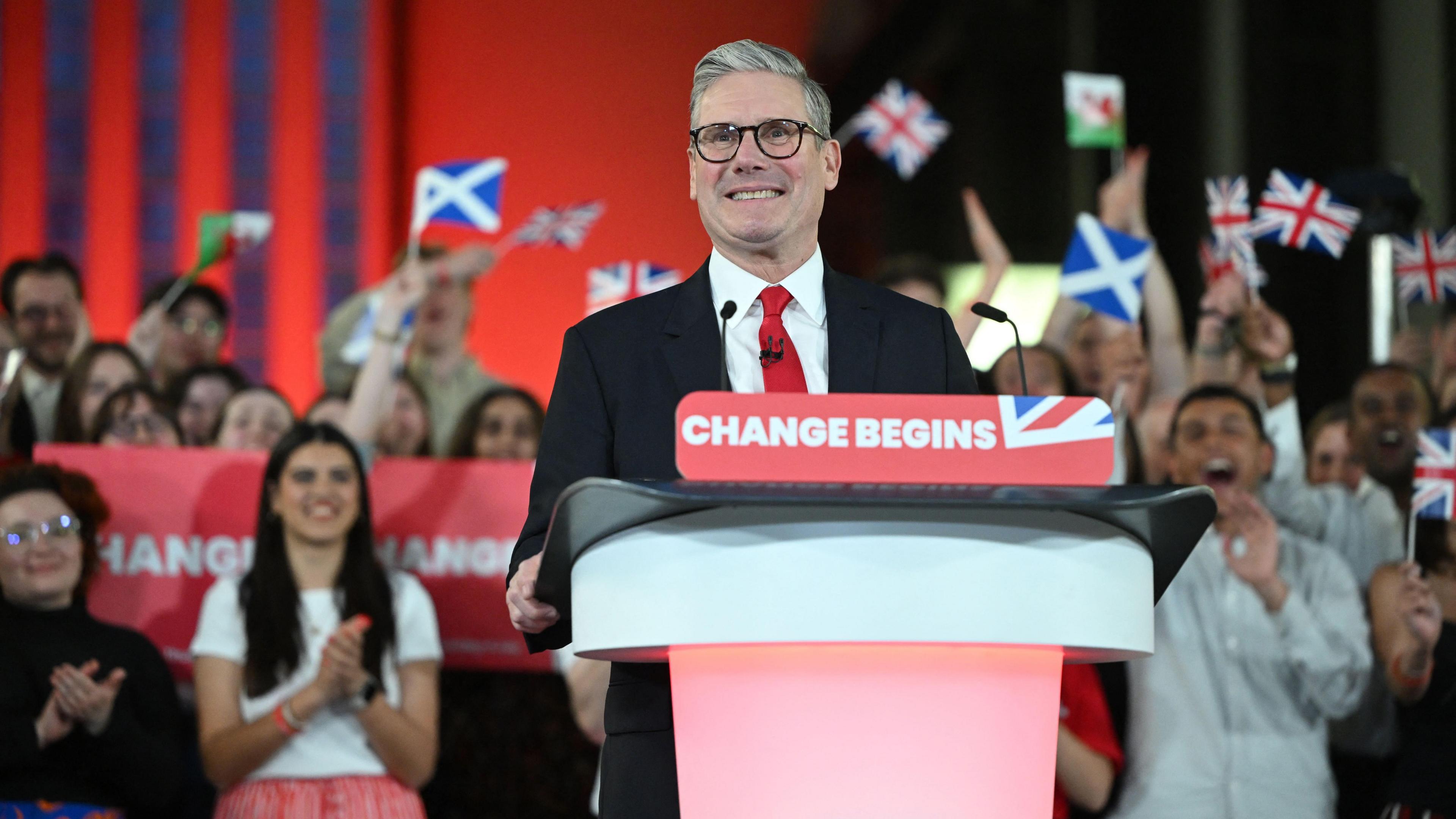 Sir Keir beams at a lectern with the banner that reads "change begins". 