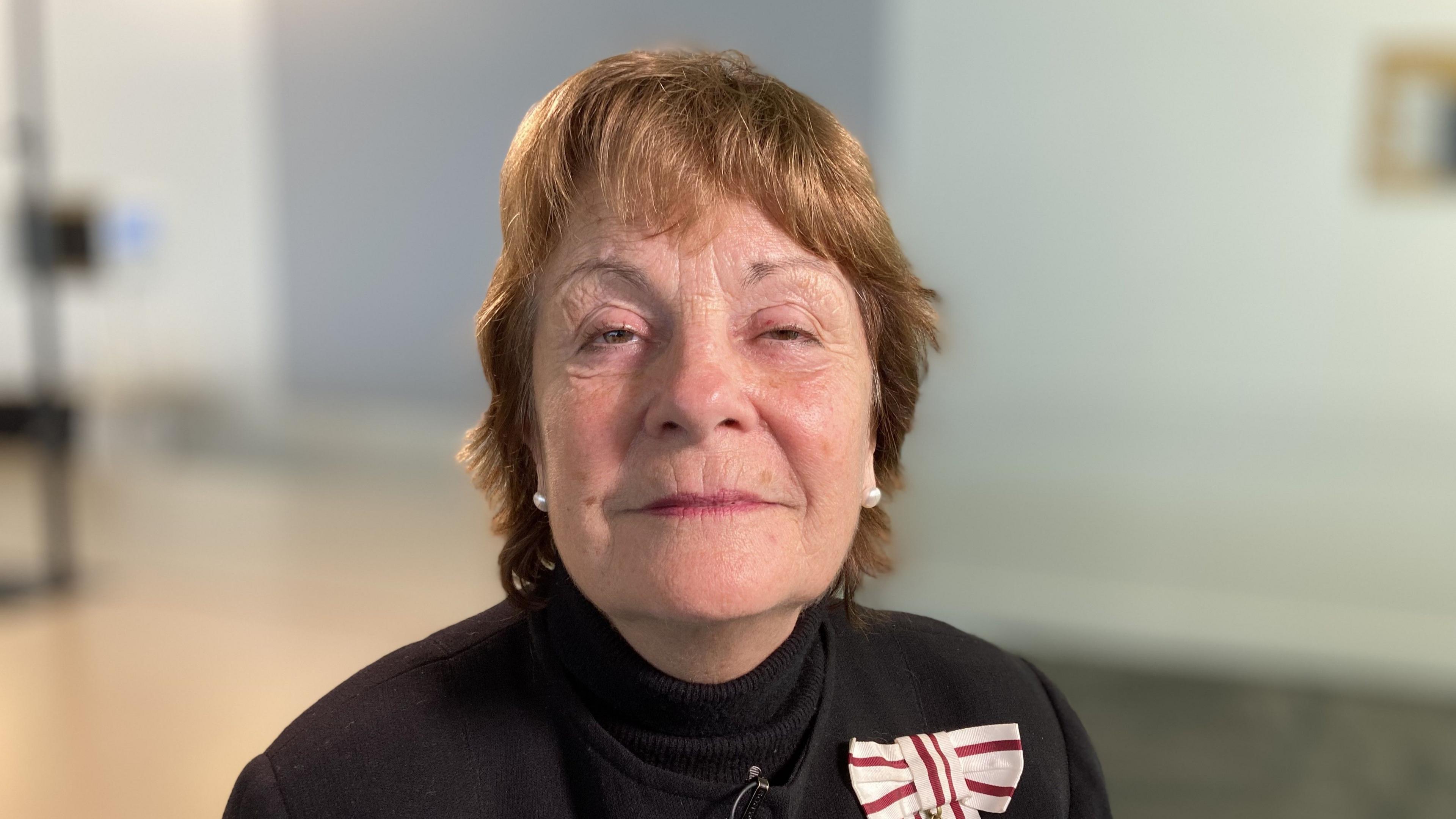 Lord Lieutenant of Suffolk, Lady Clare, Countess of Euston smiles at the camera. She has short red hair and wears pearl earrings and a black jumper.