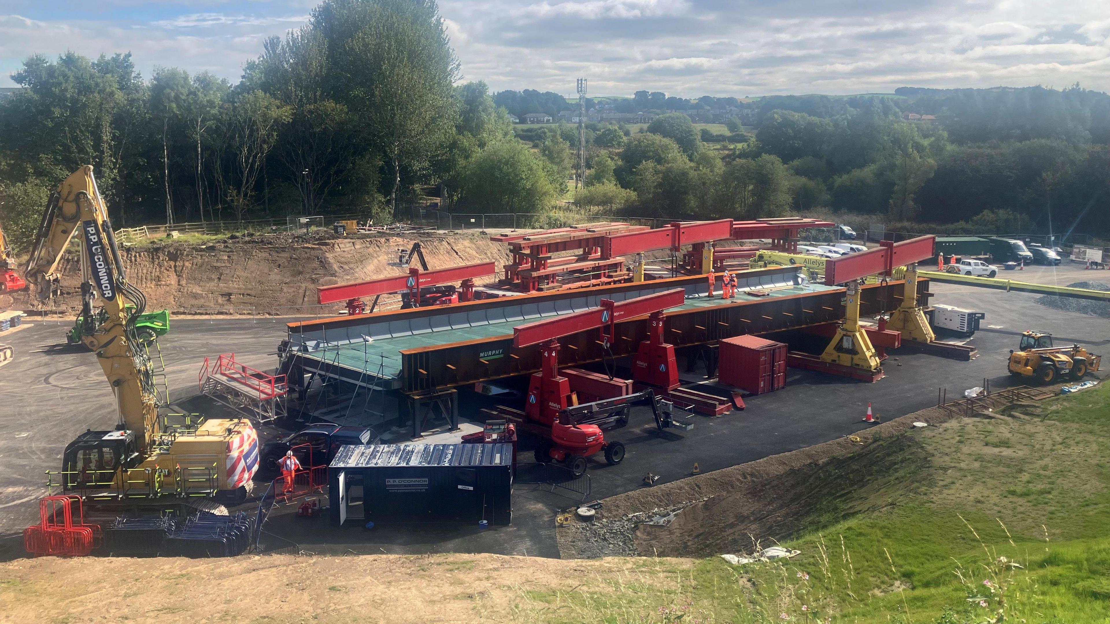 The replacement bridge held up by construction equipment at clearing made in preparation for the M62 project