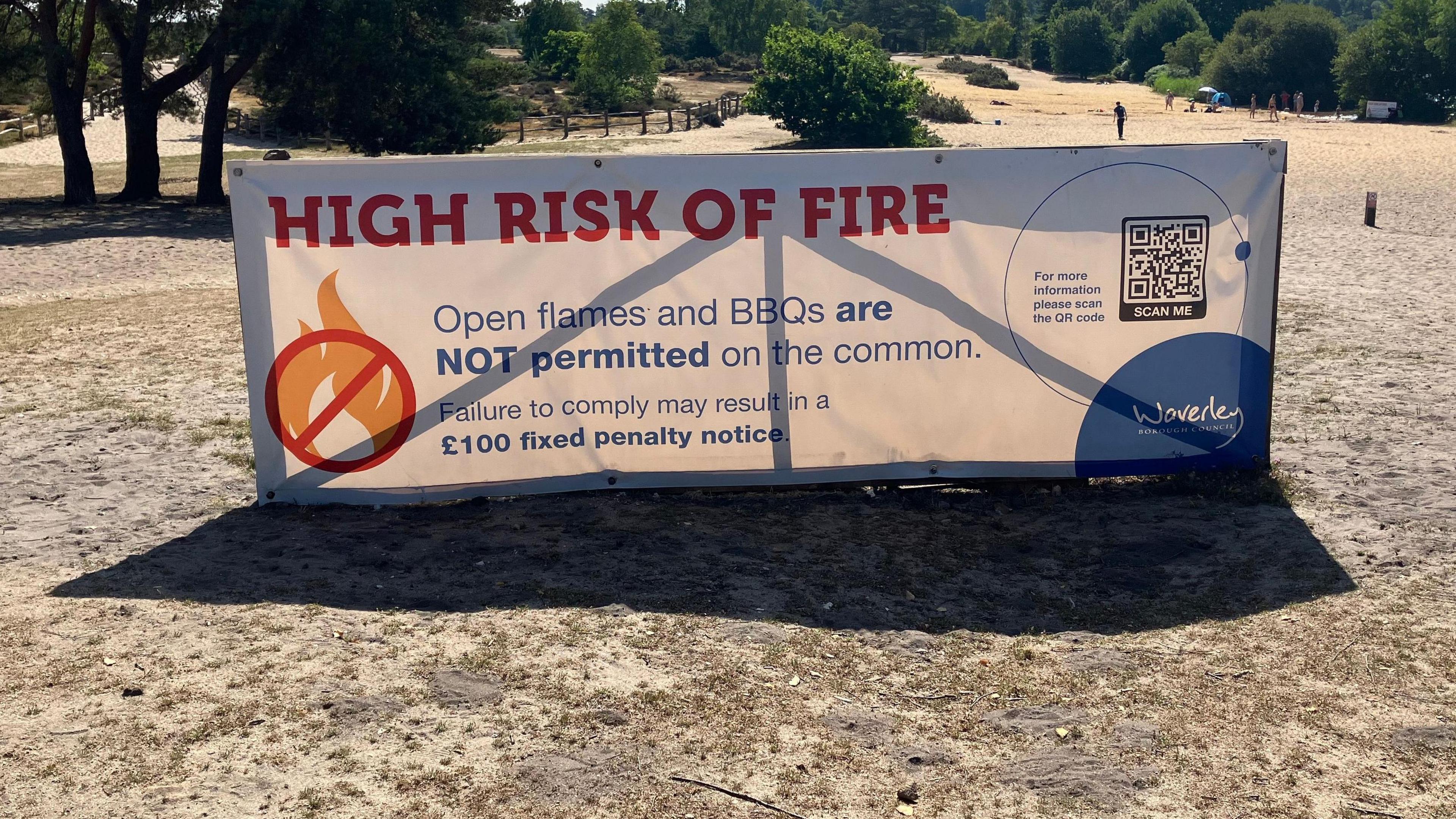 An image of a sign warning against the high risk of fire at Frensham Great Pond in Frensham, Surrey. The sign advises that open flames and BBQs are not permitted on the adjacent common.