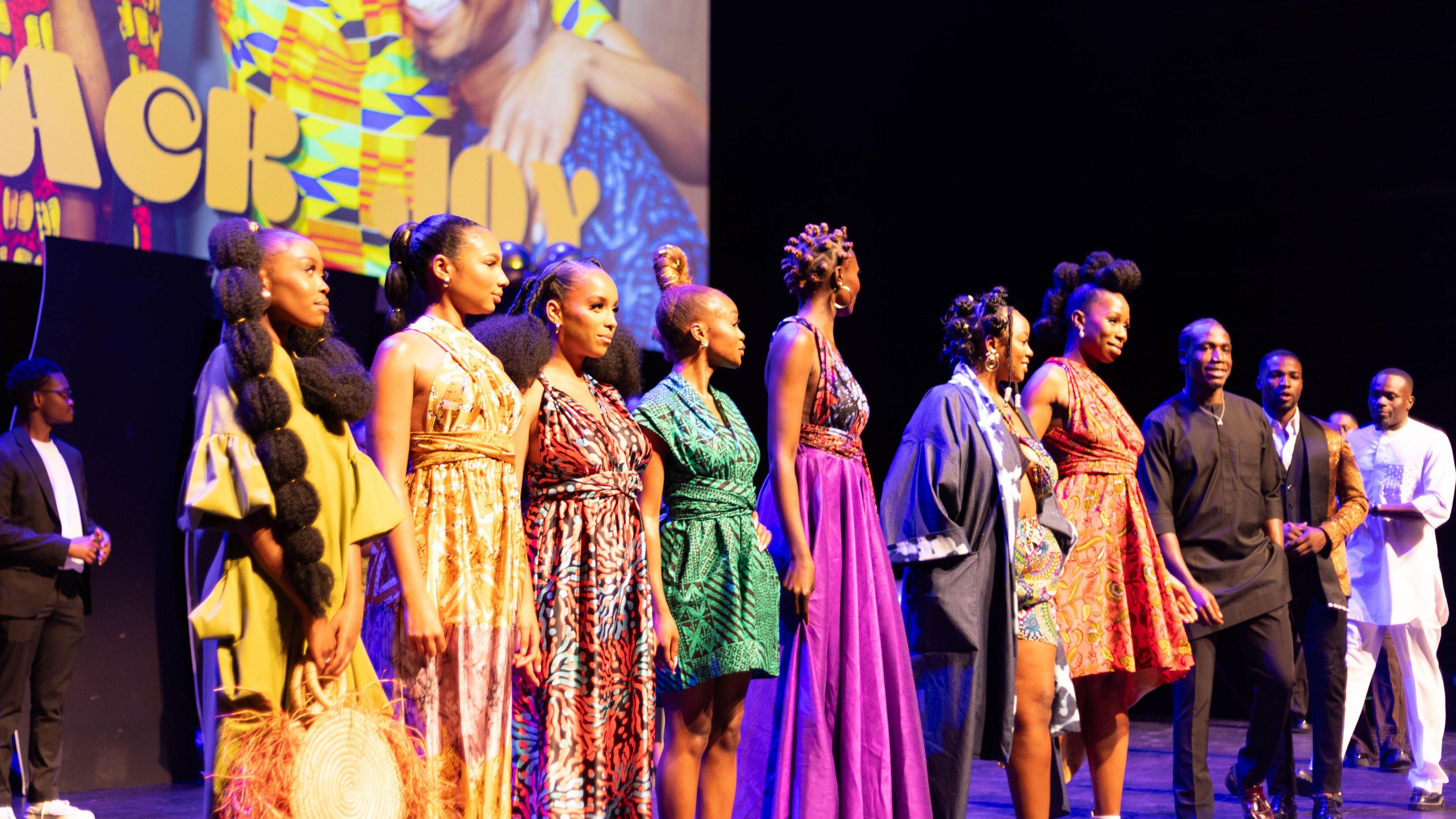 People stood on a stage at Aviva Studios in colourful clothing for an event 