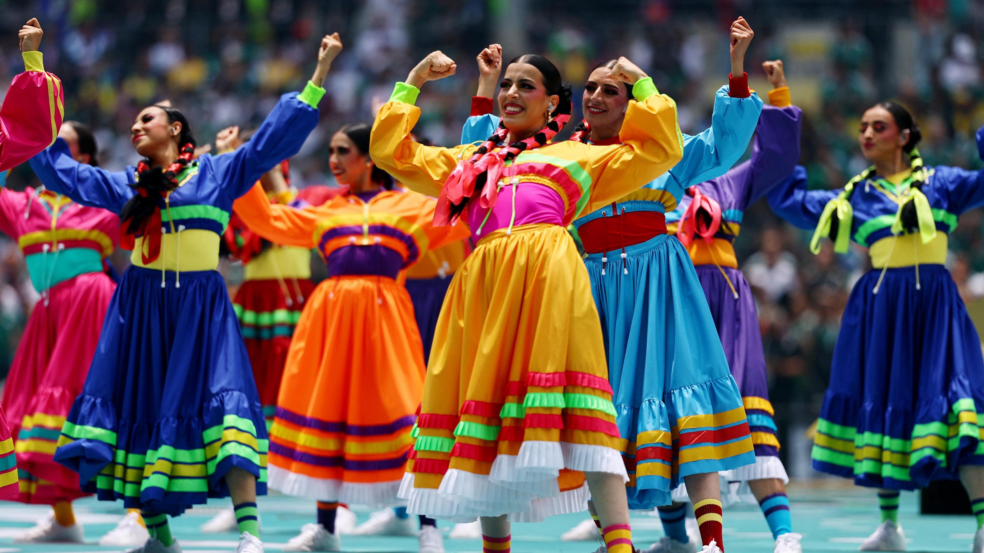 Close-up of dancers wearing colourful dresses on stage.