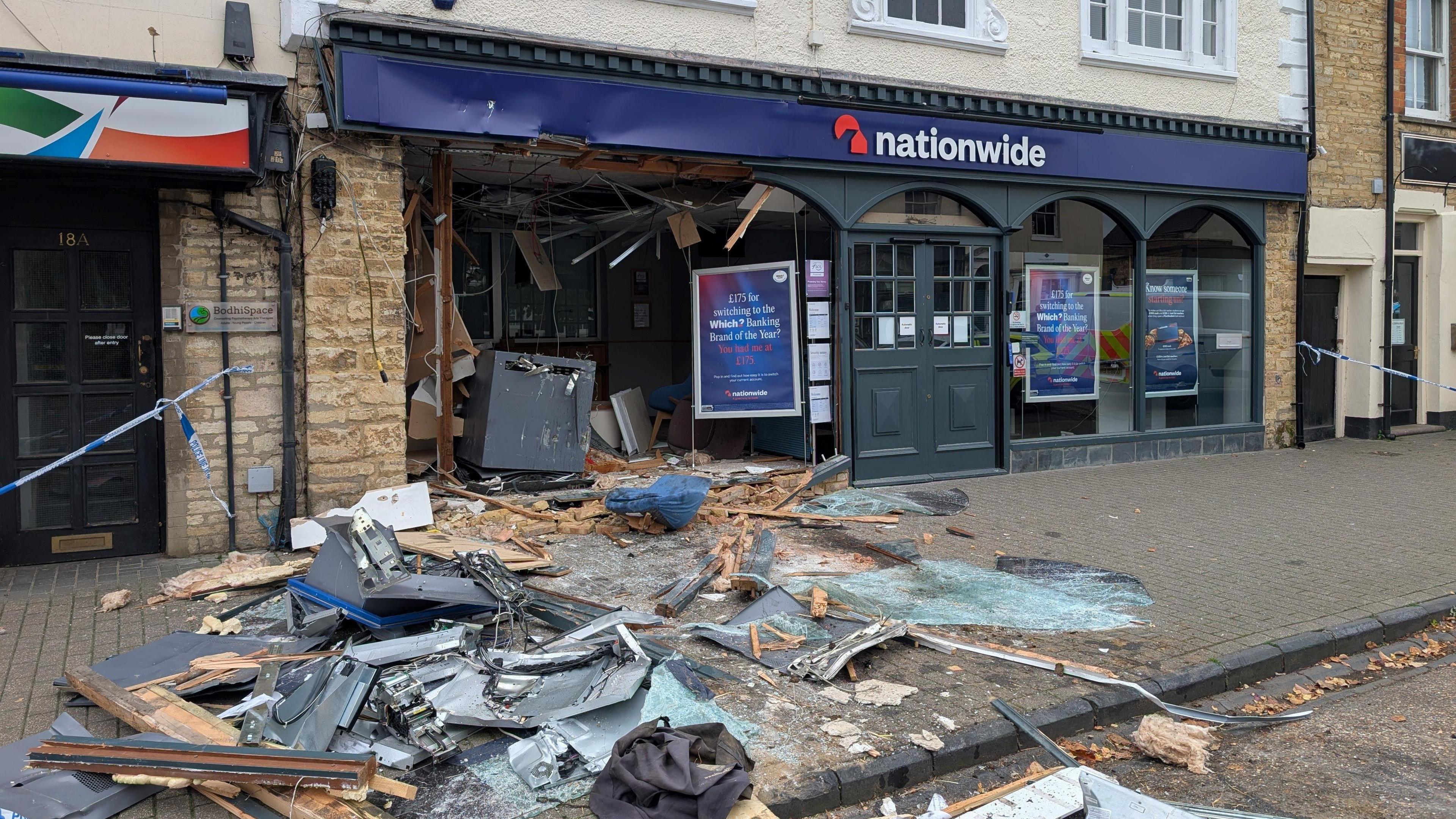 The front of Nationwide with the front of its building ripped out, showing glass, metal and wood all on the ground.
