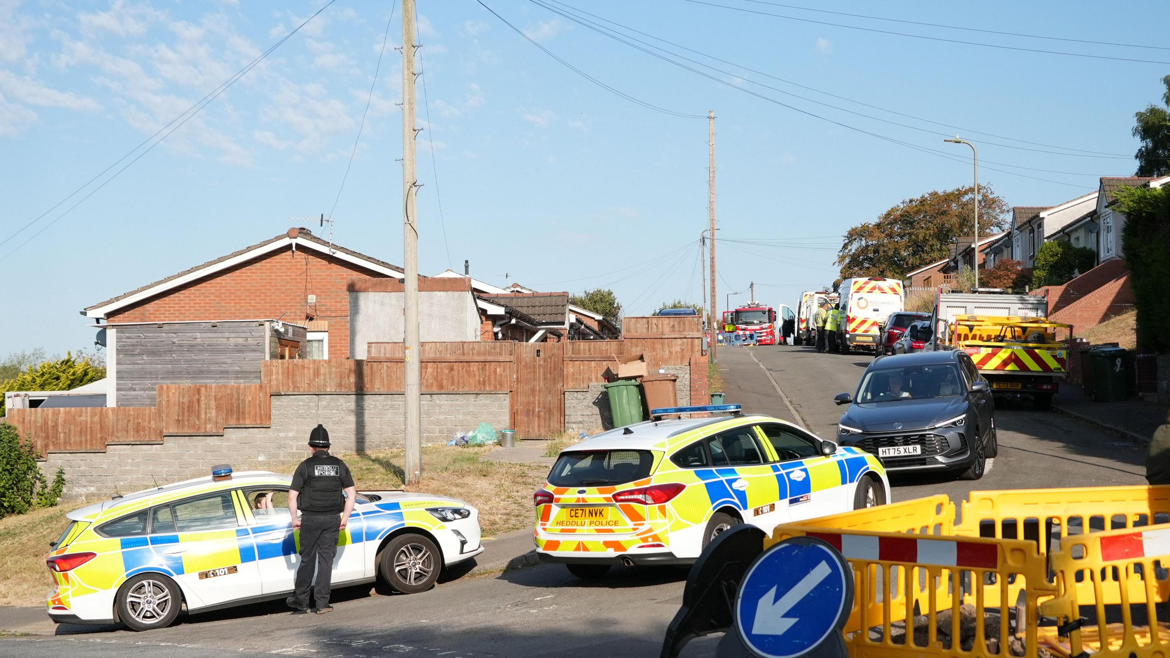 two police cars and a barrier on a residential road,.