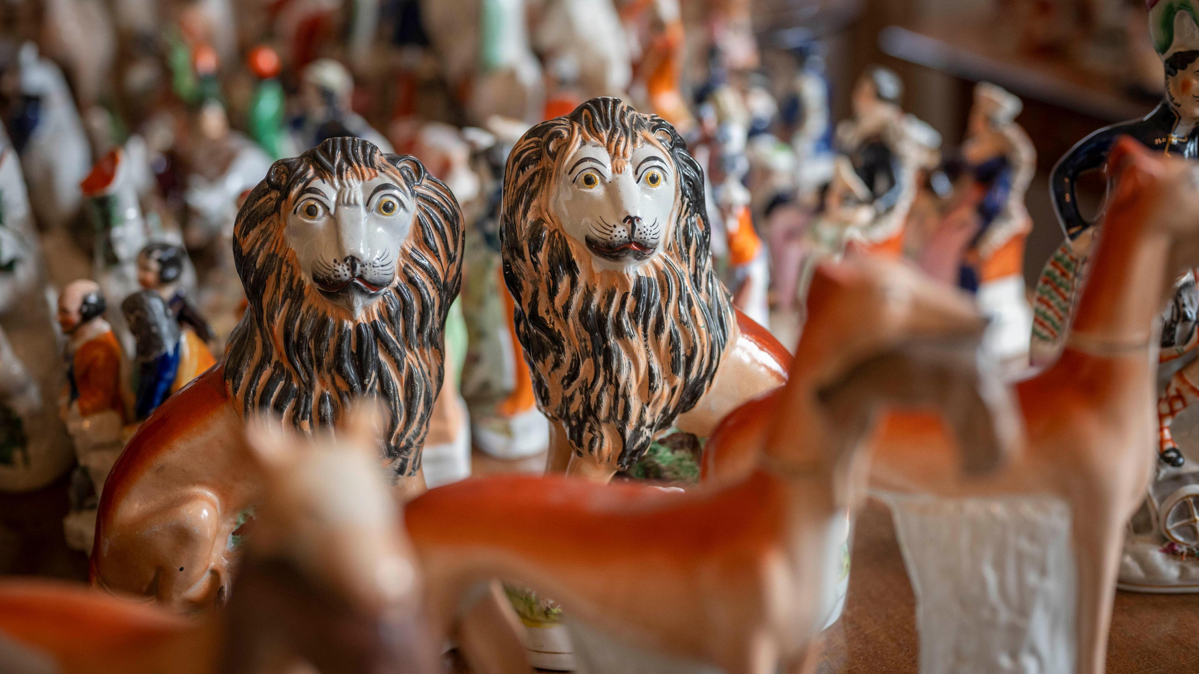 Two pottery lions with large manes stand out against a background of other blurred-out pottery figures