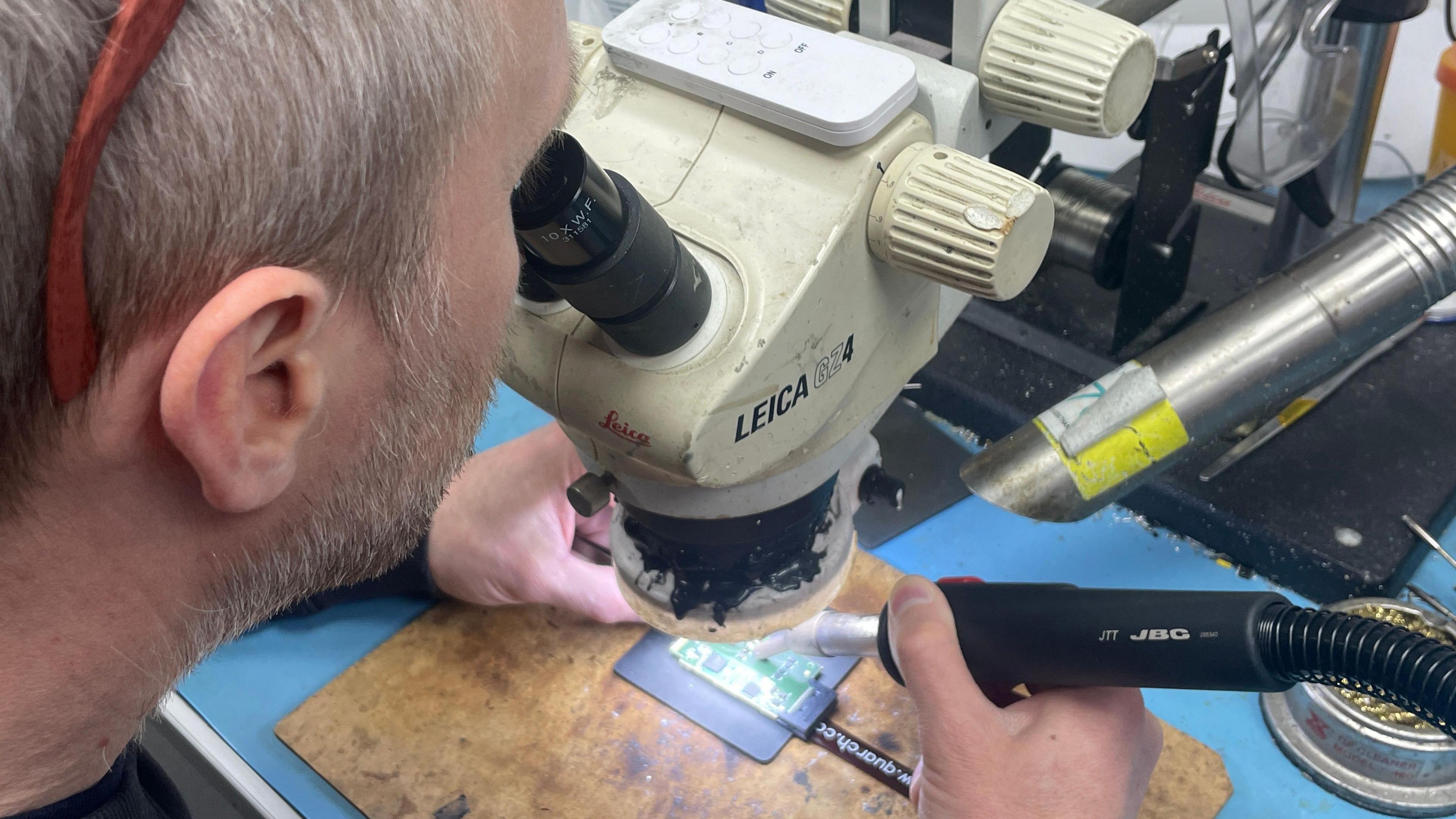 Neach-obrach aig Quarch Technology a' coimhead tro mhicroscope