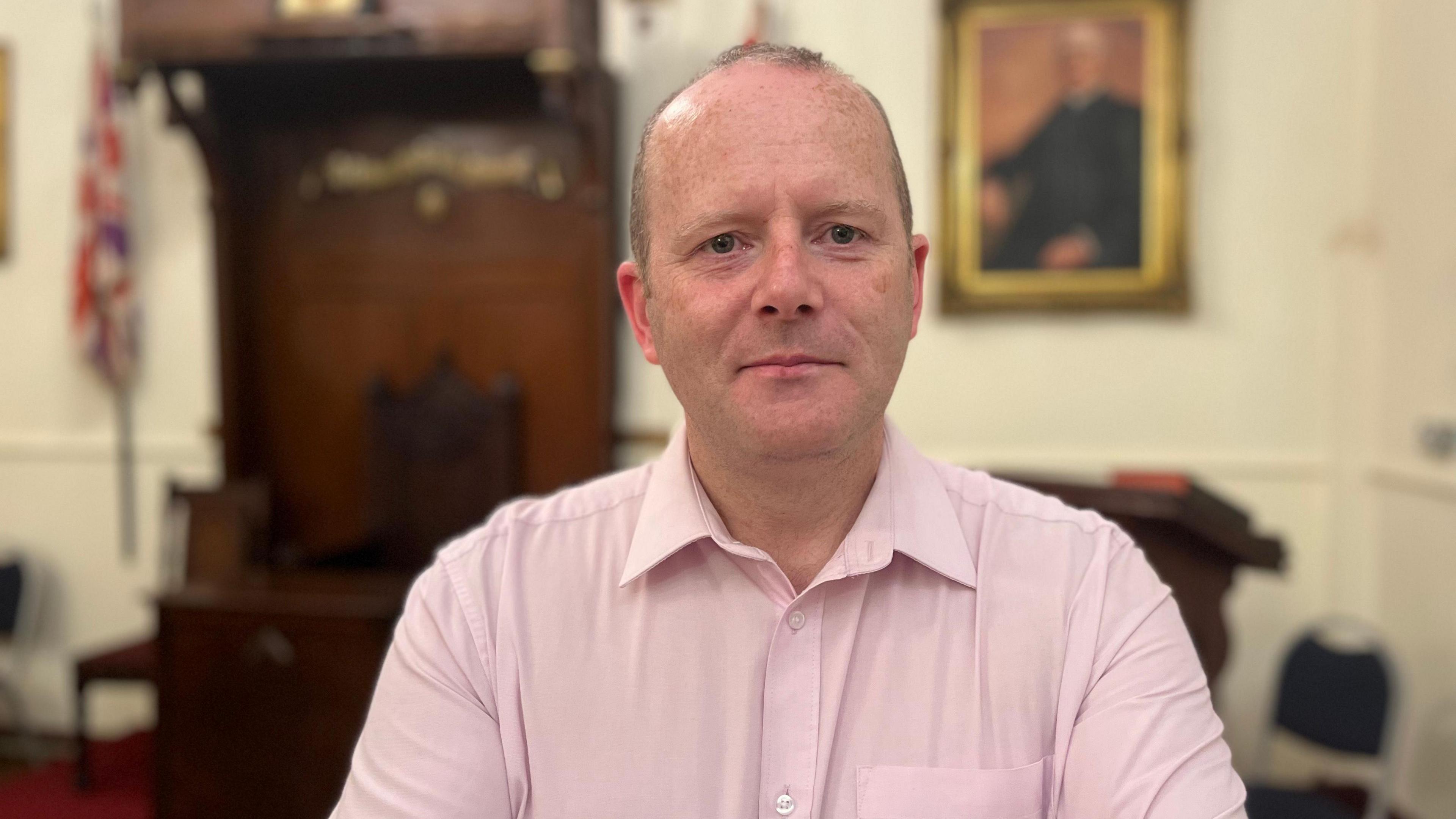 A man in a pink shirt with short hair