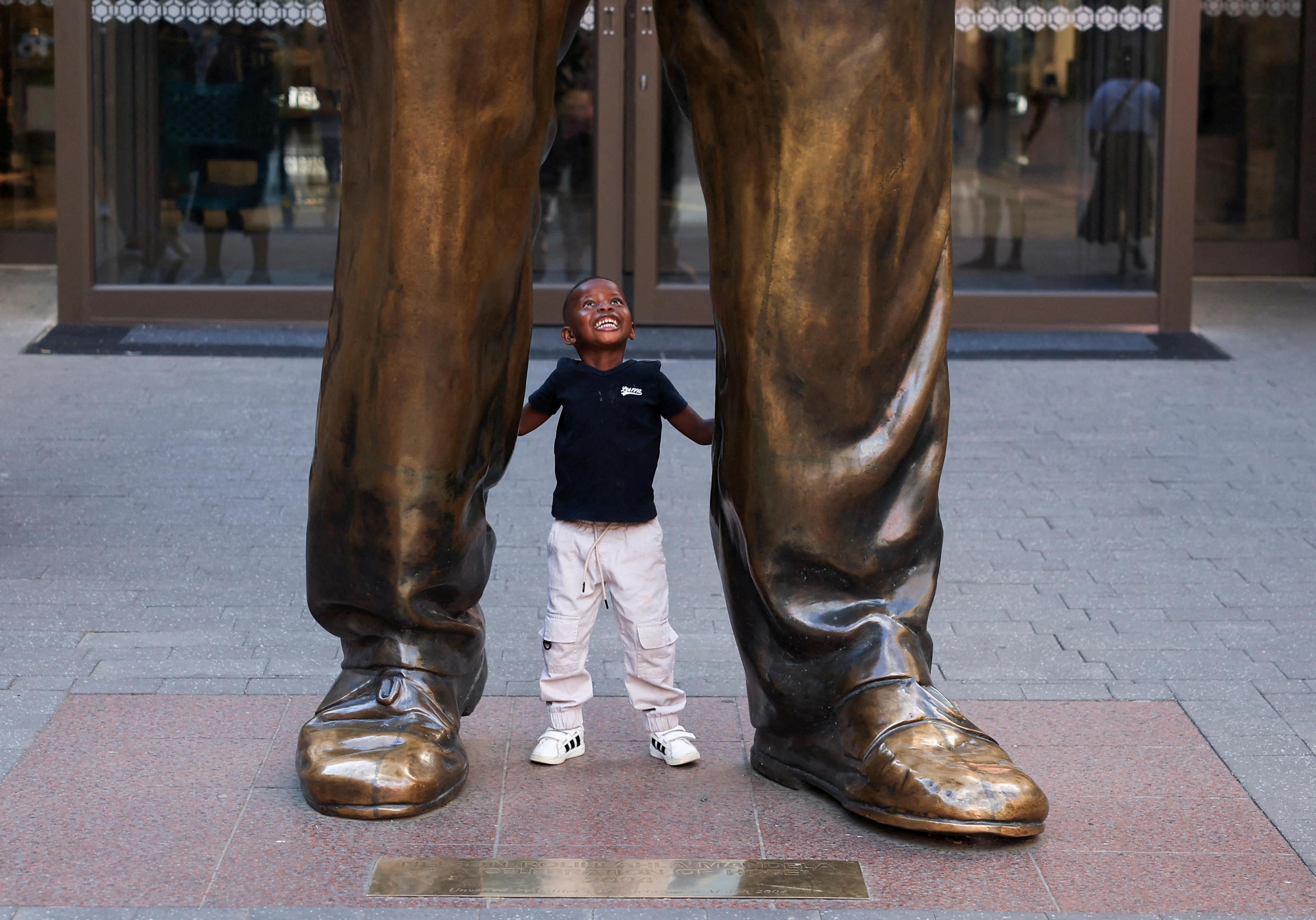 A boy plays at the feet of a statue of former South African President Nelson Mandela on Nelson Mandela Square in Sandton, Johannesburg.