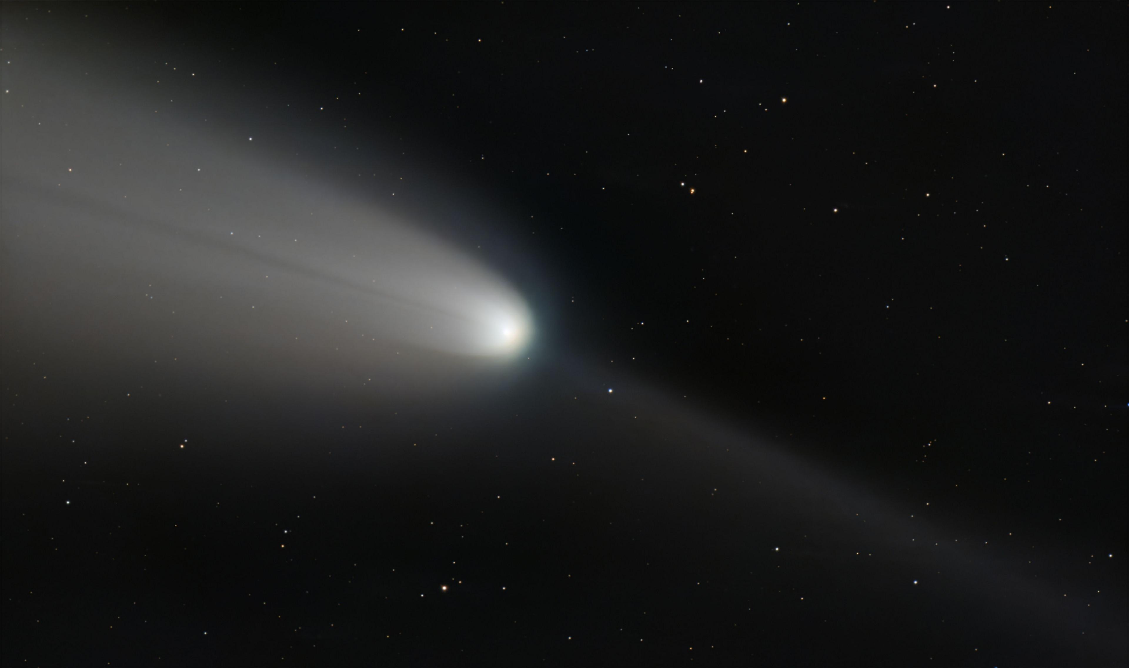 "C/2023 A3 (Tsuchinshan−ATLAS), known as the Great Comet of 2024, shoots across a black inky sky scattered with small stars as a bright white light.