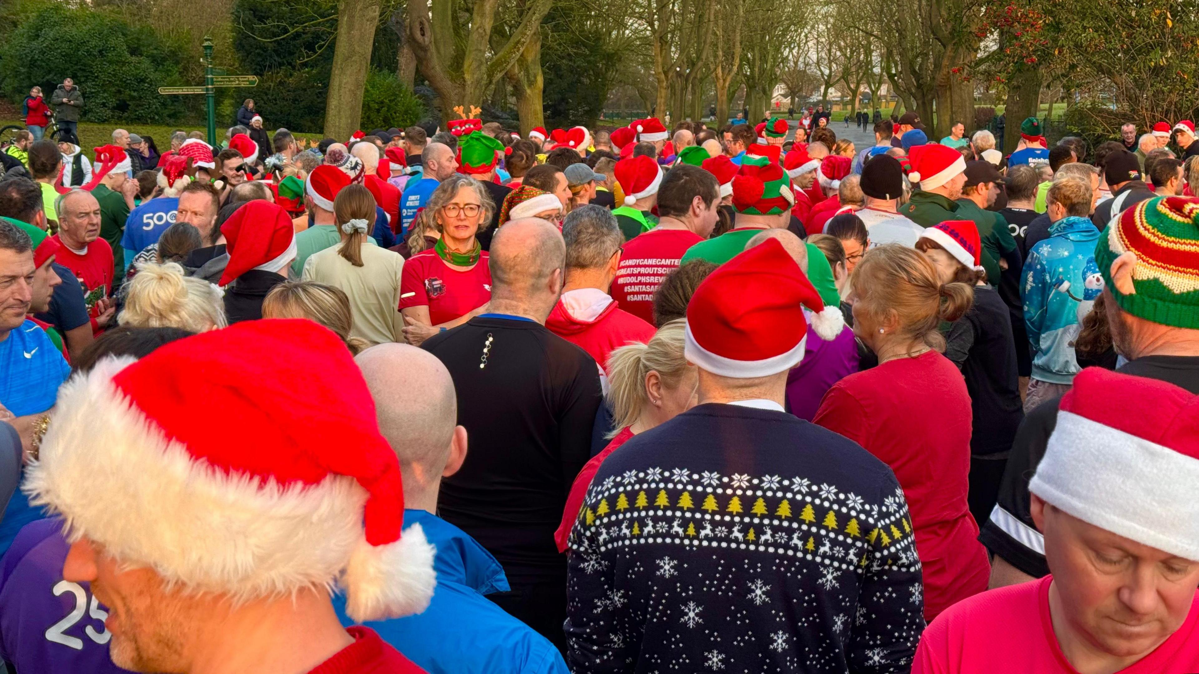 A group of people wearing colourful clothes and Santa hats.