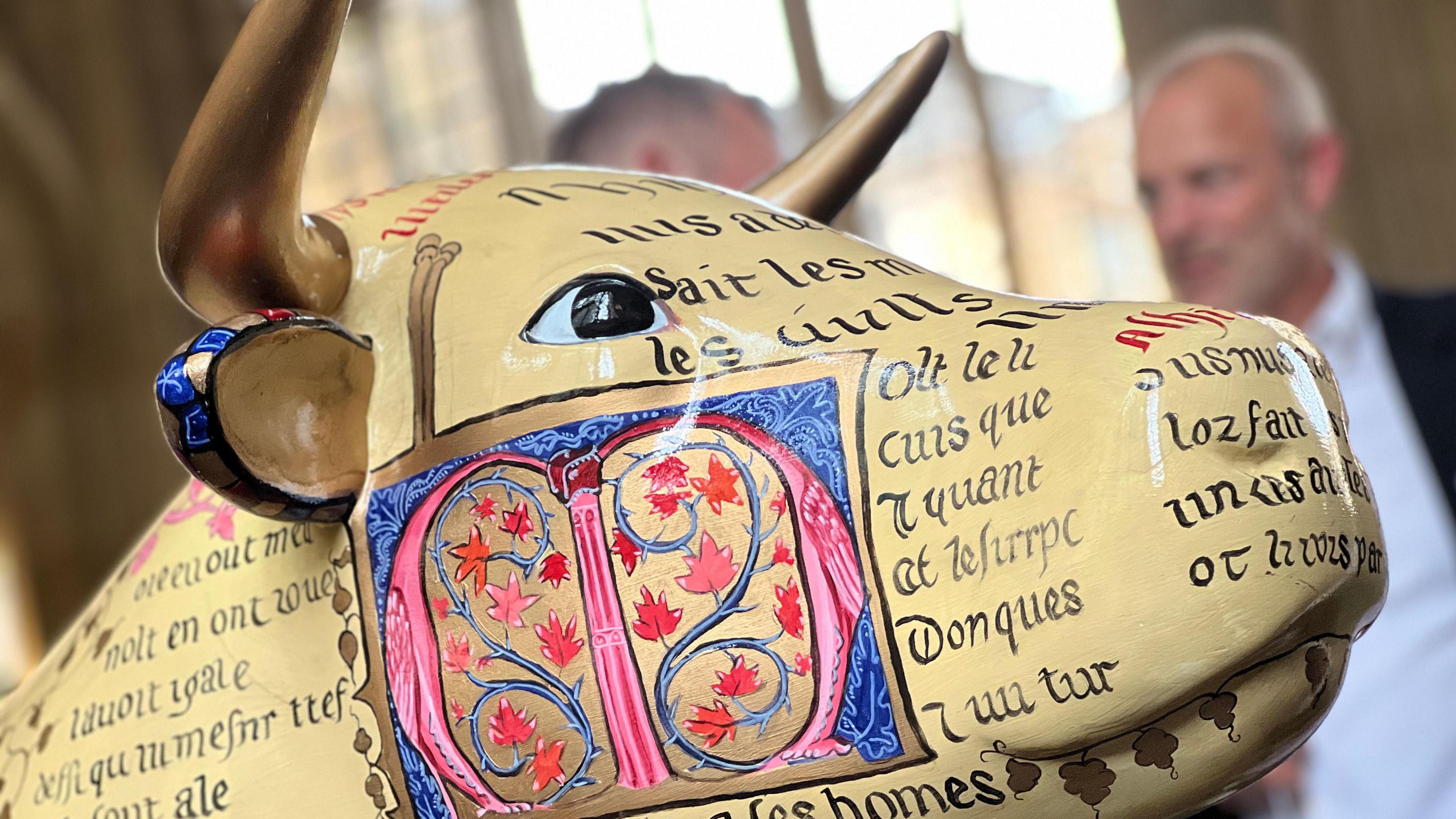 a close-up image of a ox sculpture face with writing and art across it.