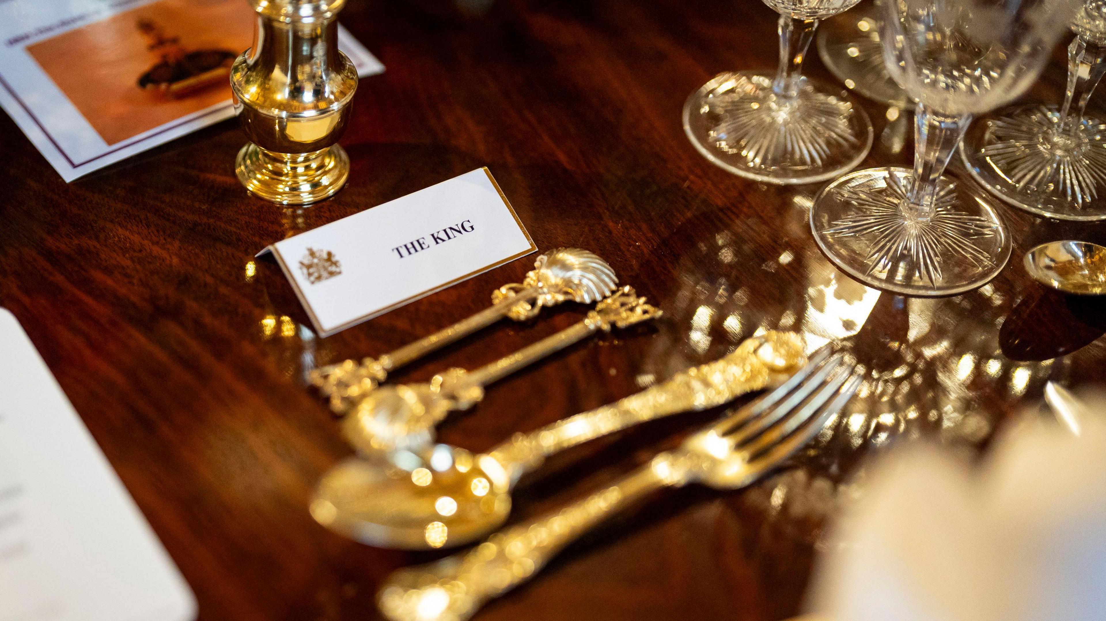 A place settings at the banquet table reads THE KING and has gold cutlery next to it